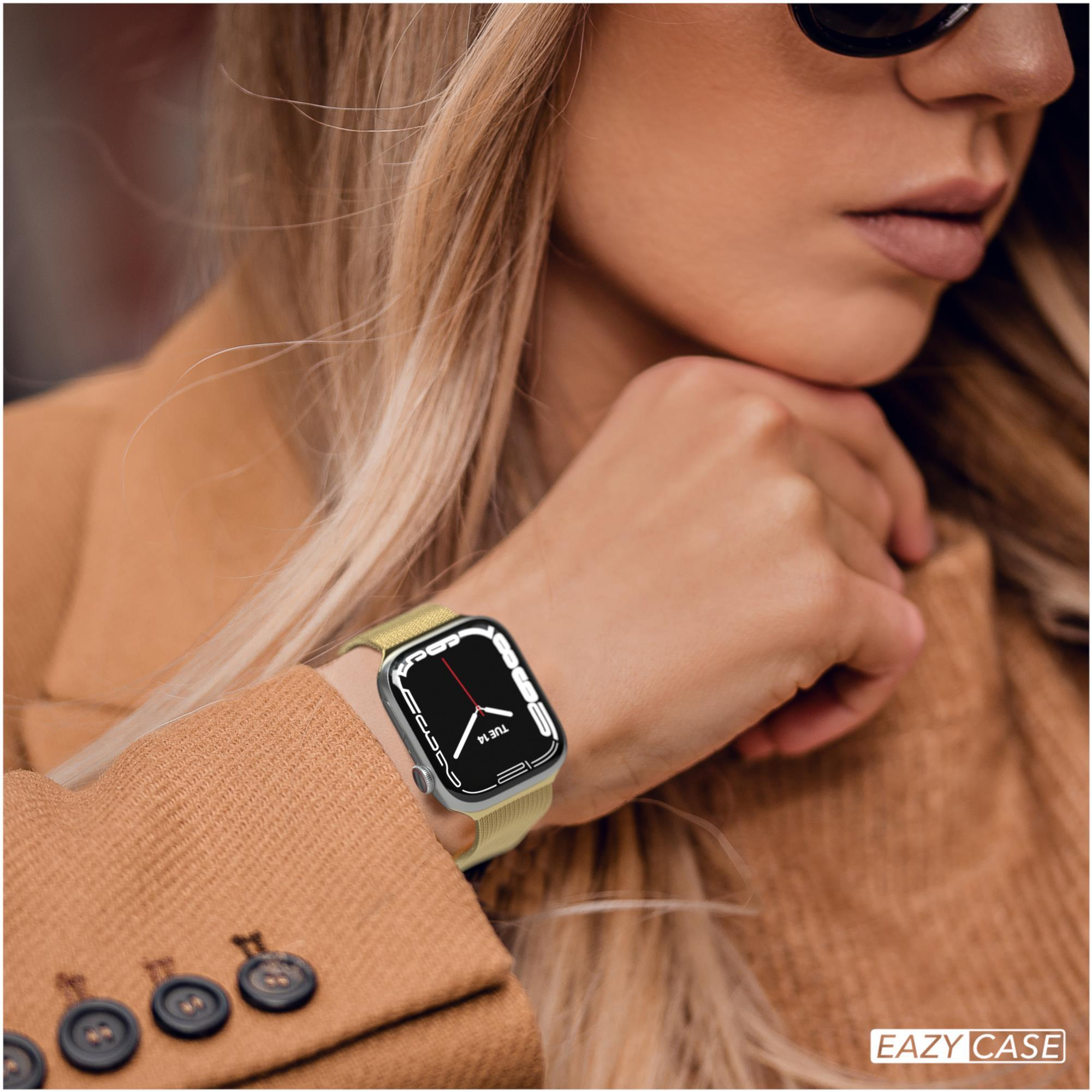 Eine Frau mit Sonnenbrille und beigem Mantel hat eine Smartwatch am Handgelenk. Die Uhr zeigt das Datum an.