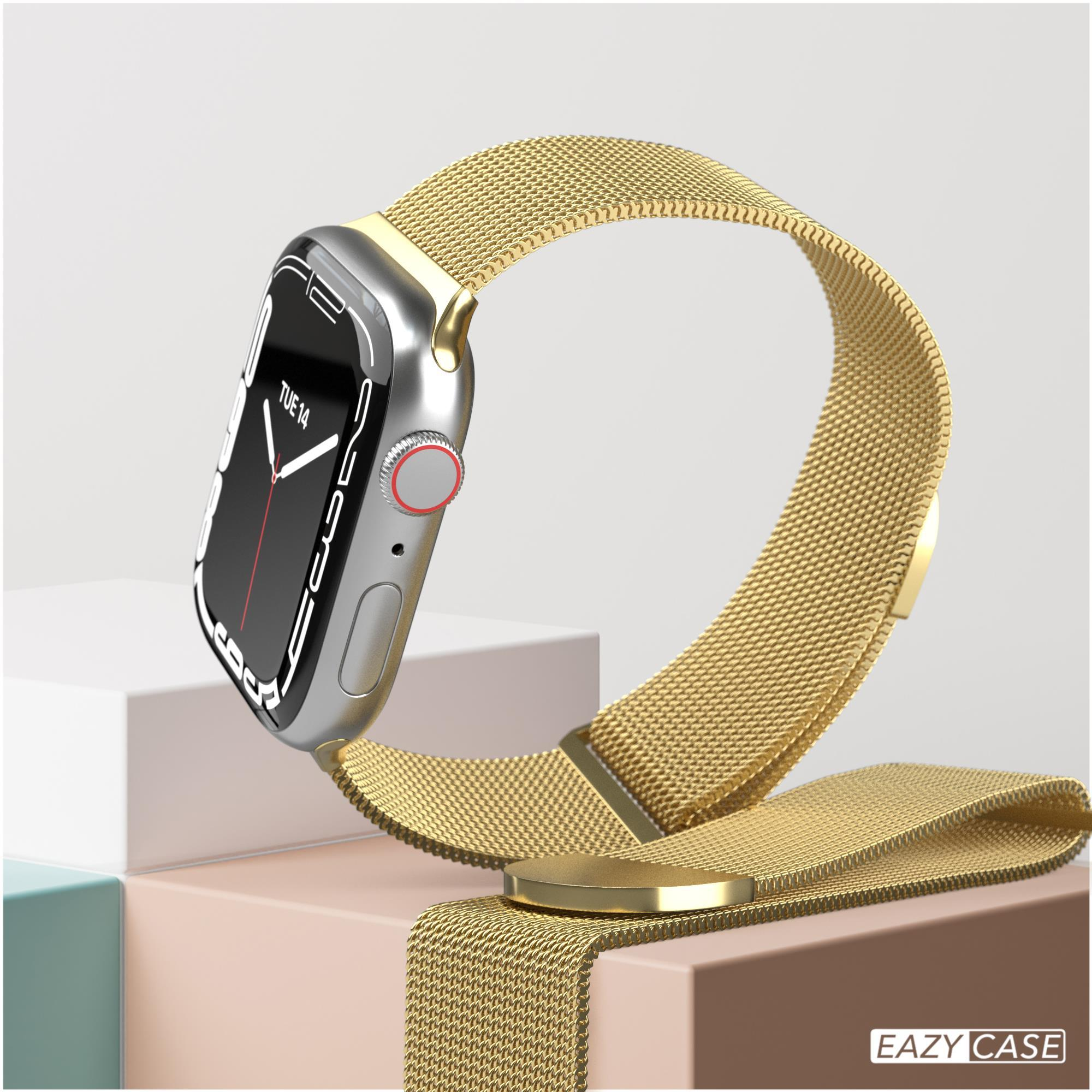 Eine goldene Uhr mit Mesh-Armband auf weißer und rosa Oberfläche.