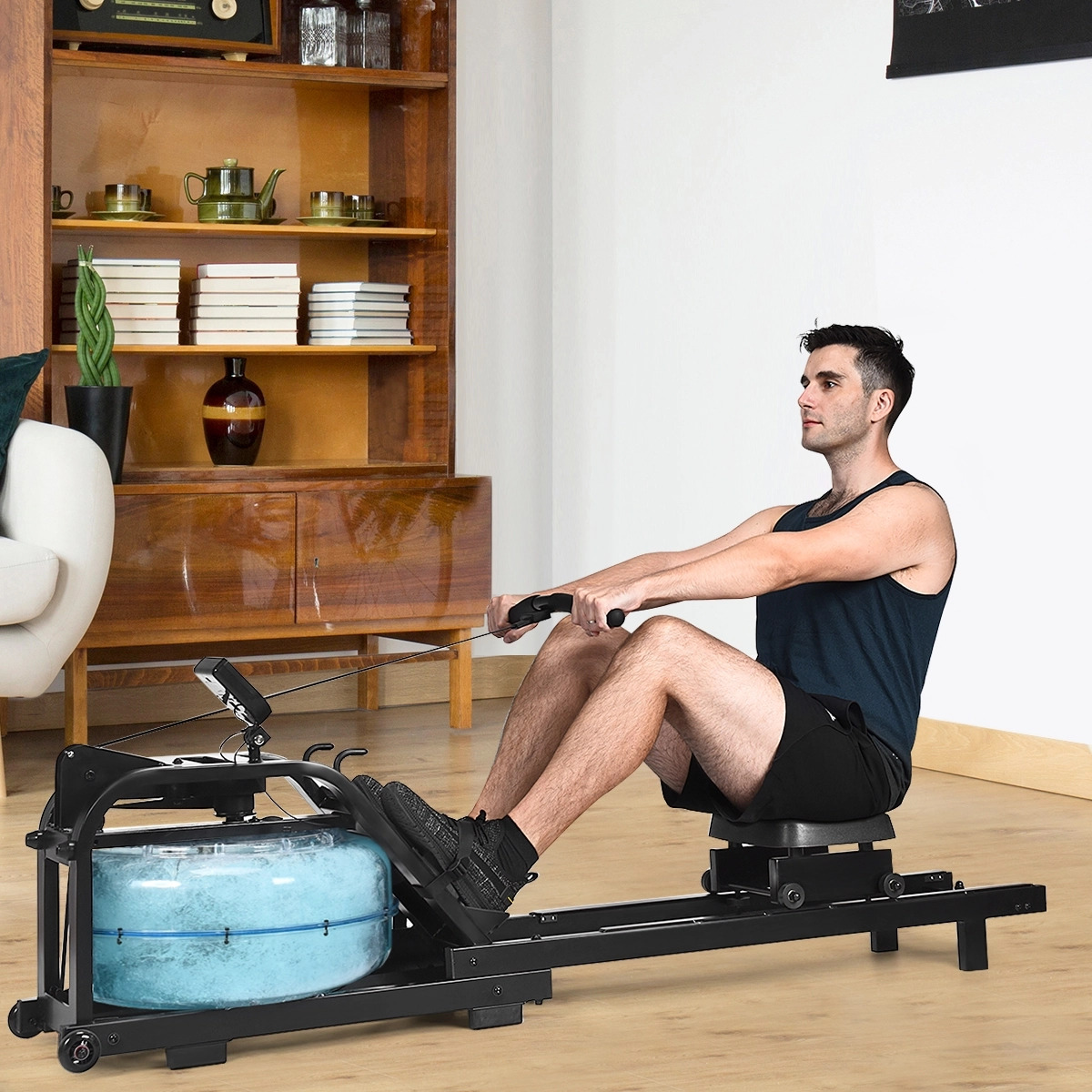 Homme utilisant un rameur aquatique à l'intérieur. Il porte des vêtements de sport, ramant vers la caméra.