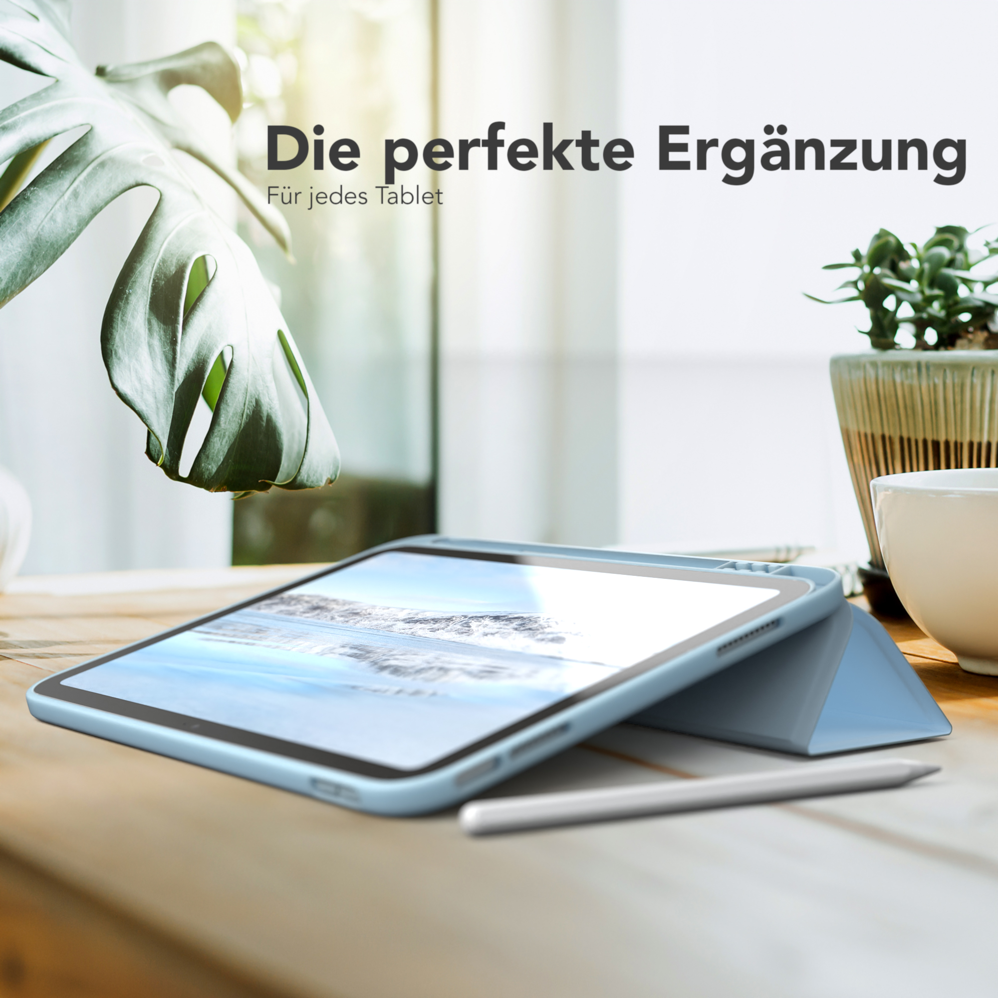 Ein Tablet in hellblauer Hülle, mit Stift, auf einem Holztisch, neben einer Pflanze.