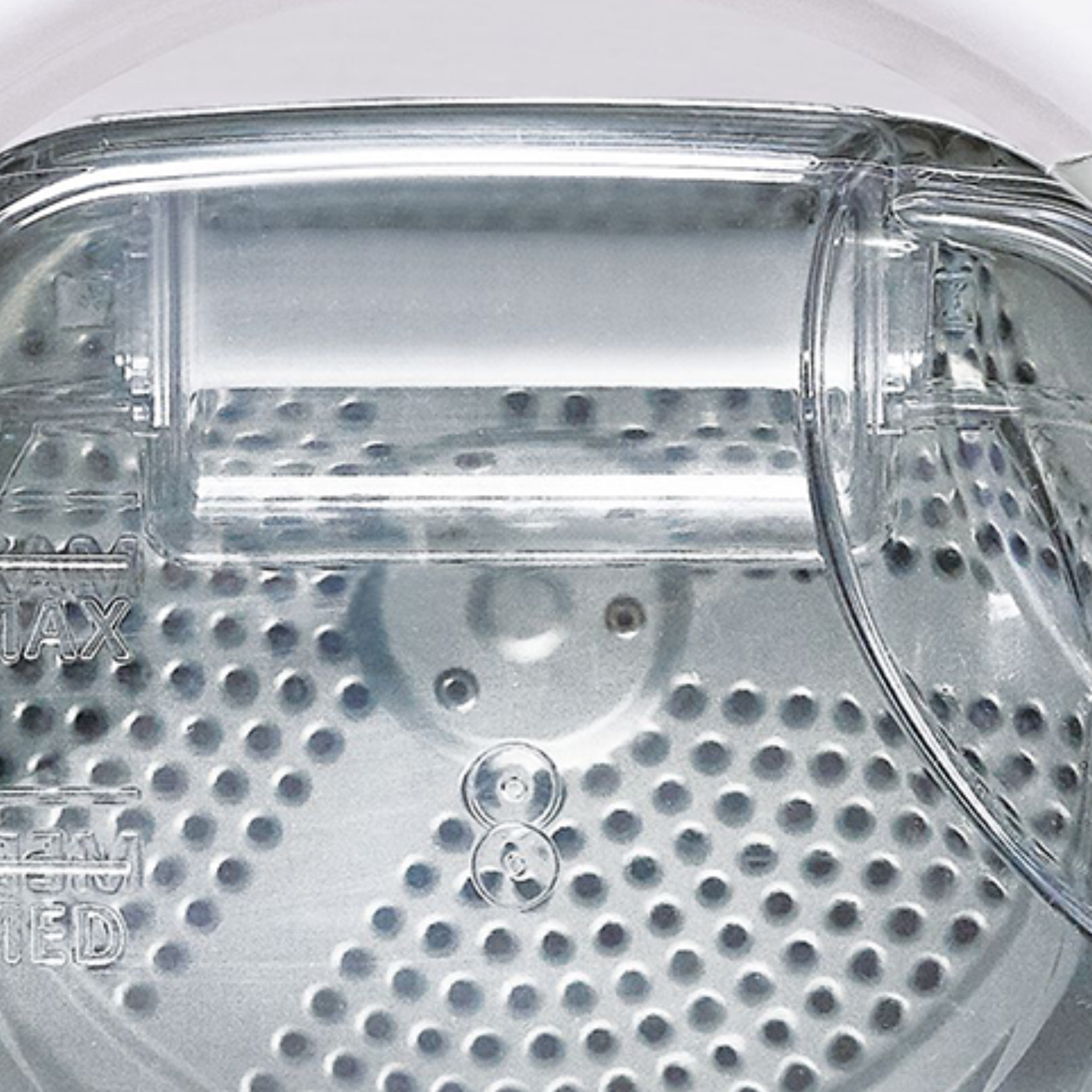 Zbliżenie białego, przezroczystego bębna suszarki z perforowanym wnętrzem.