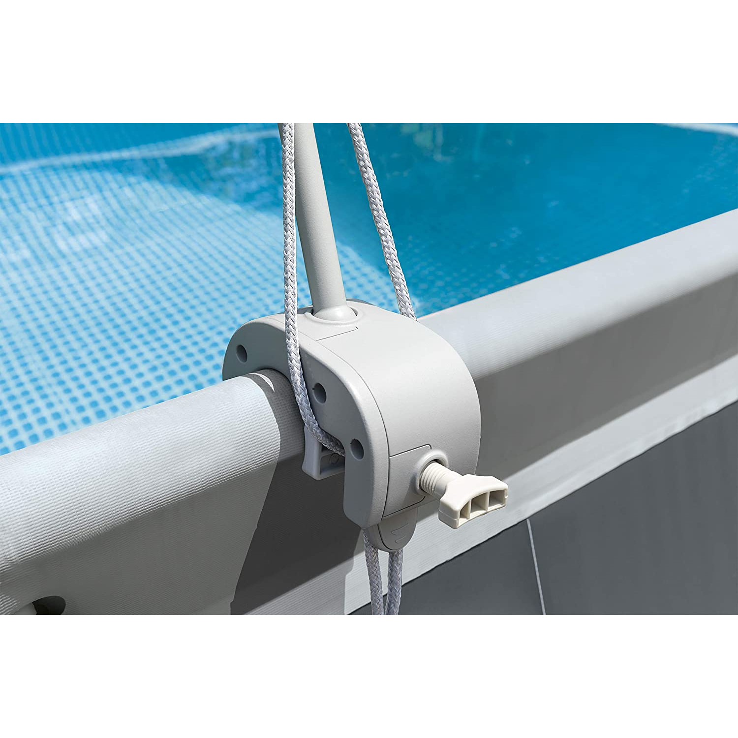 Poolabdeckungsmechanismus mit weißem Seil und grauer Kunststoffkomponente. Blauer Pool im Hintergrund.