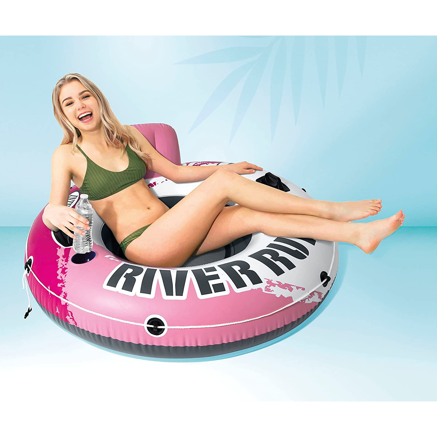 Frau im Bikini auf pinkfarbenem Fluss-Schwimmer, hält Wasserflasche. Blauer Hintergrund.