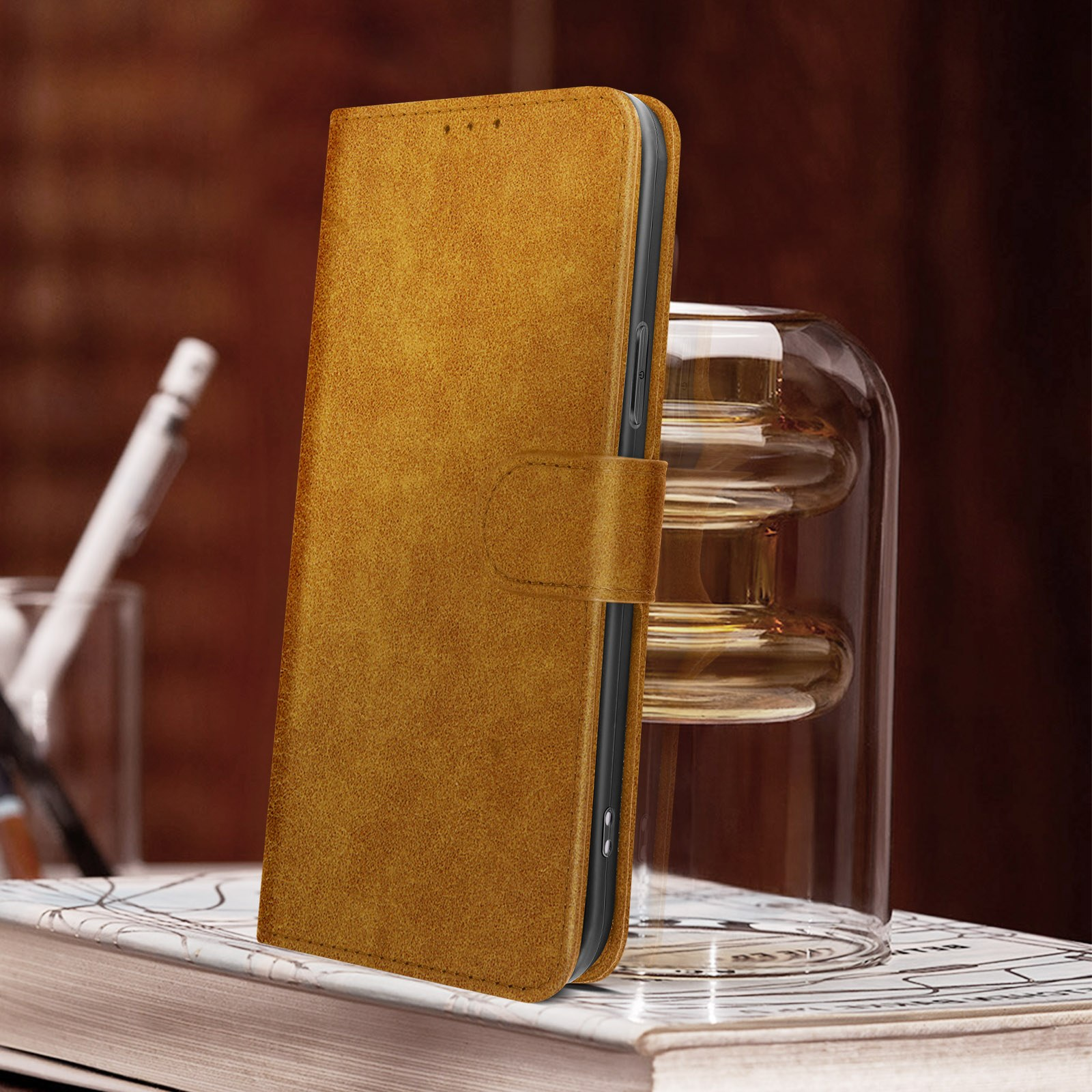 Braune Leder-Handyhülle, geöffnet, um das Telefon zu zeigen. Glasvase und Stift im Hintergrund.