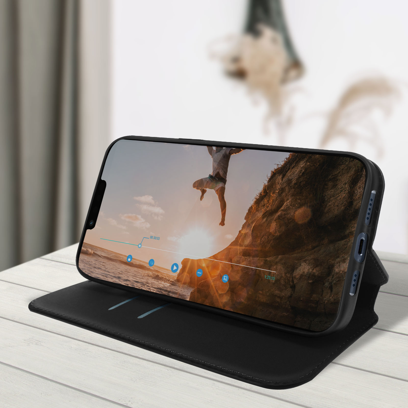 Een smartphone met een video die afspeelt op een zwarte hoes, op een witte houten tafel.