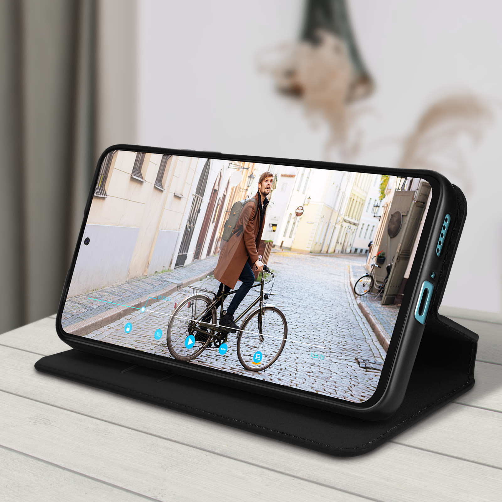 Uno smartphone in una custodia nera mostra un uomo in bicicletta in una strada europea. La custodia è aperta.
