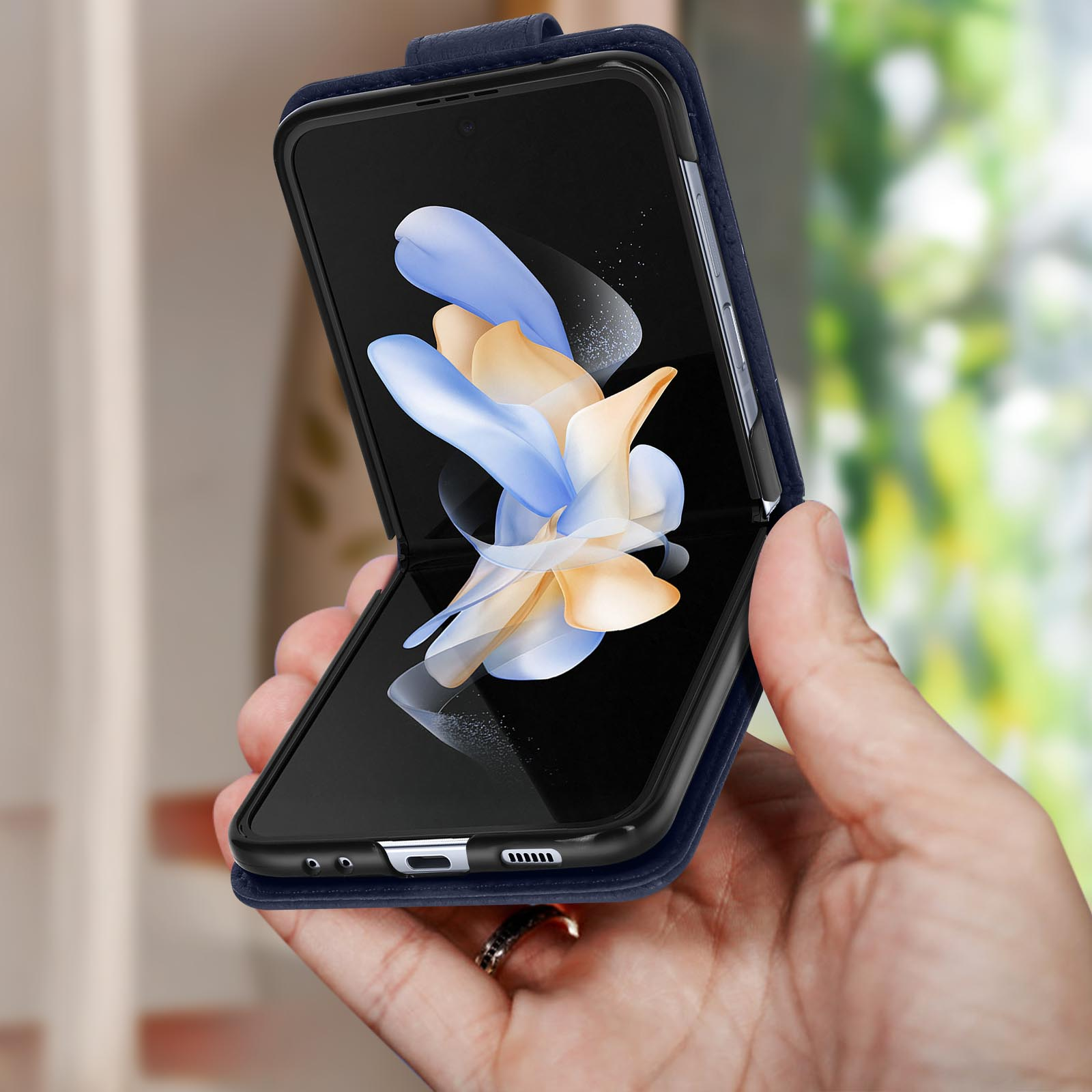 Een opvouwbare telefoon wordt in een hand gehouden. Het scherm toont abstracte graphics. De achtergrond is wazig.