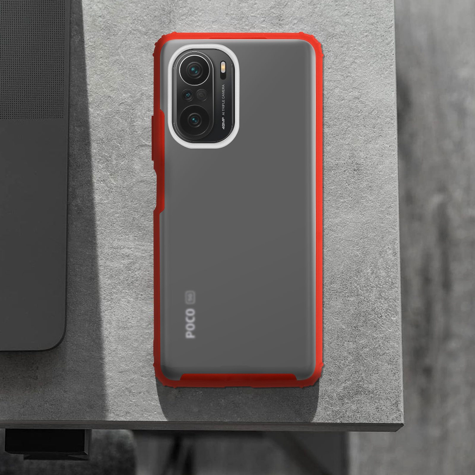 Una custodia per telefono con bordo rosso su un tavolo. Il telefono ha tre fotocamere.