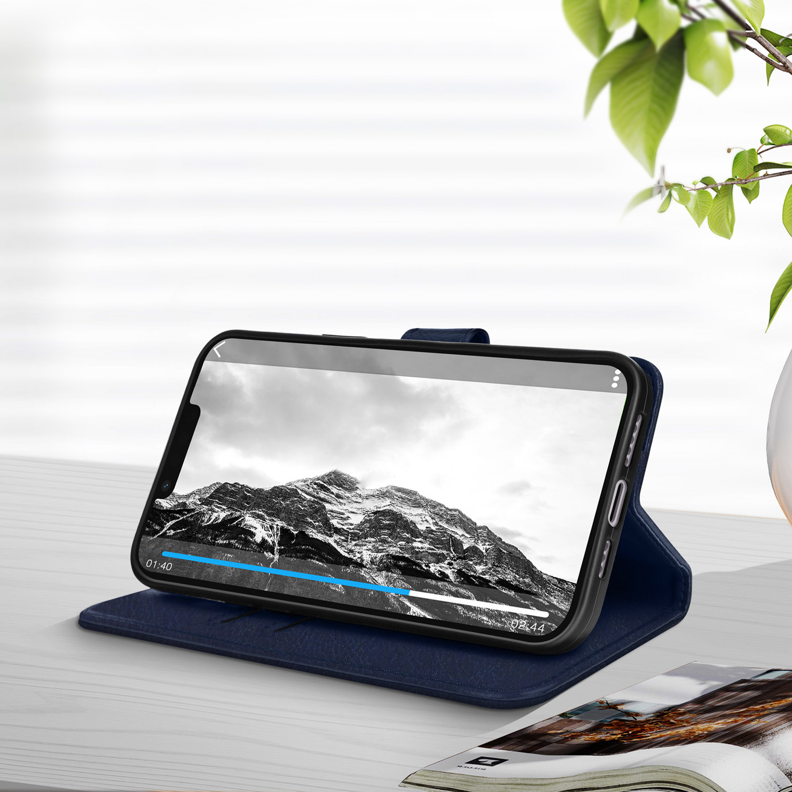 Een telefoon in een blauwe hoes, met een video op het scherm, liggend op een tafel met een tijdschrift.