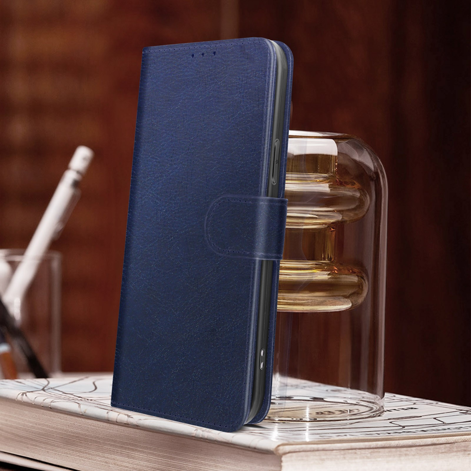 Blauwe leren telefoonhoes met een boek en glazen vaas op de achtergrond.