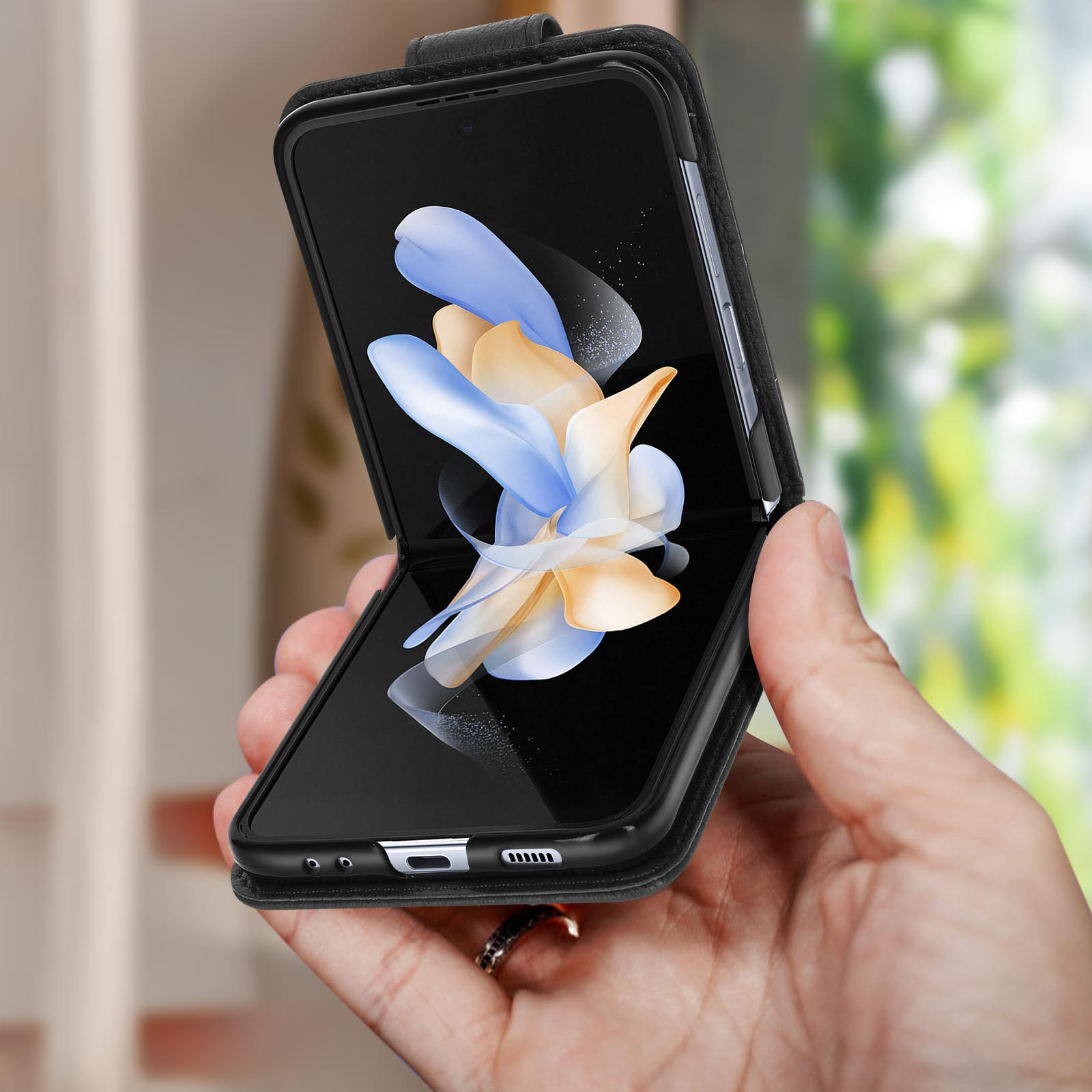 Una mano che tiene una custodia per telefono nera aperta con un telefono che mostra un'immagine colorata.