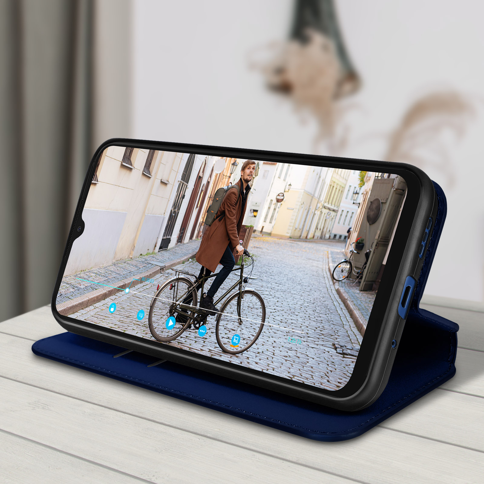 Ein Telefon in einer blauen Hülle, das einen Mann zeigt, der mit dem Fahrrad durch eine Kopfsteinpflasterstraße fährt.