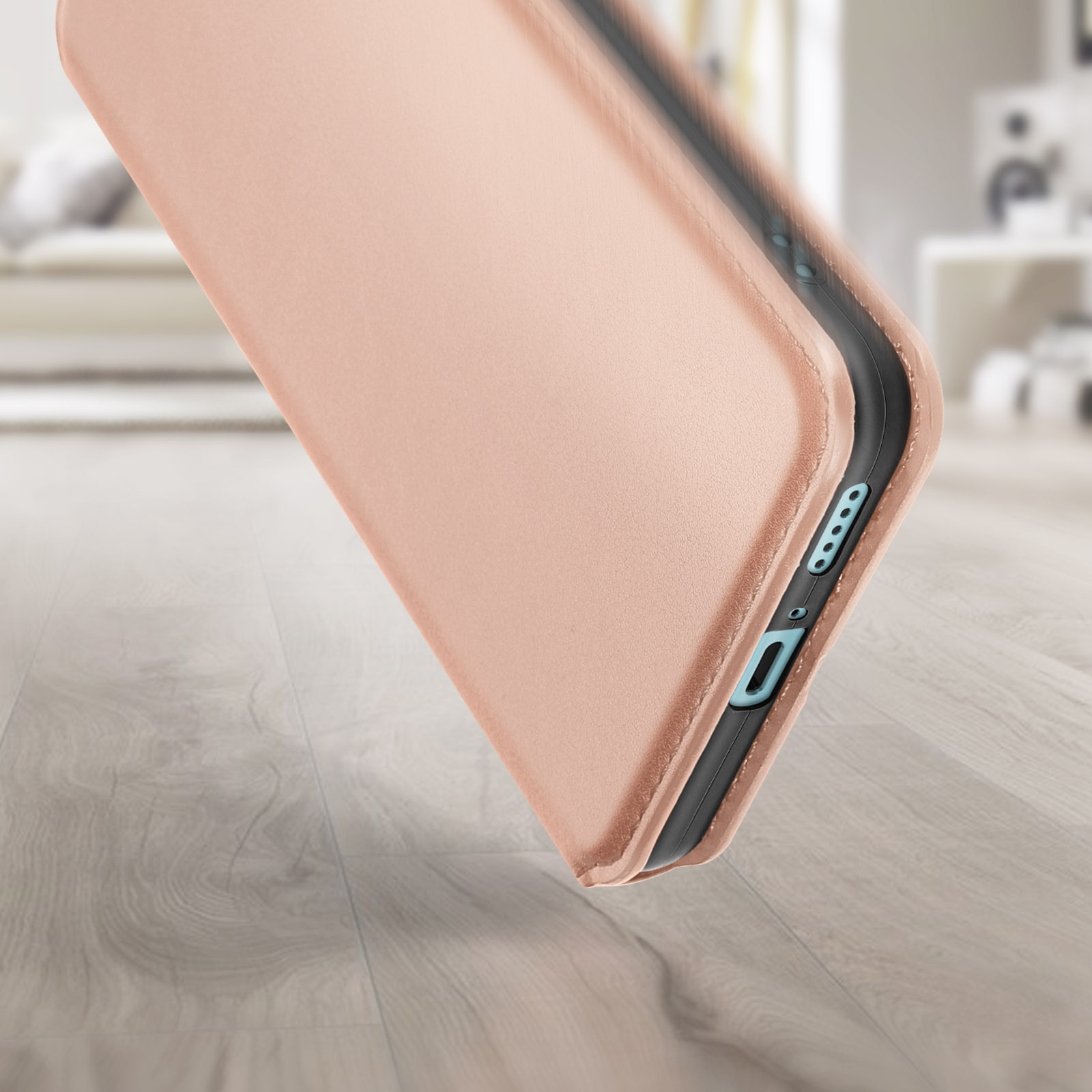 Una custodia per telefono color oro rosa è sollevata, mostrando il lato del telefono, un pavimento in legno sullo sfondo.