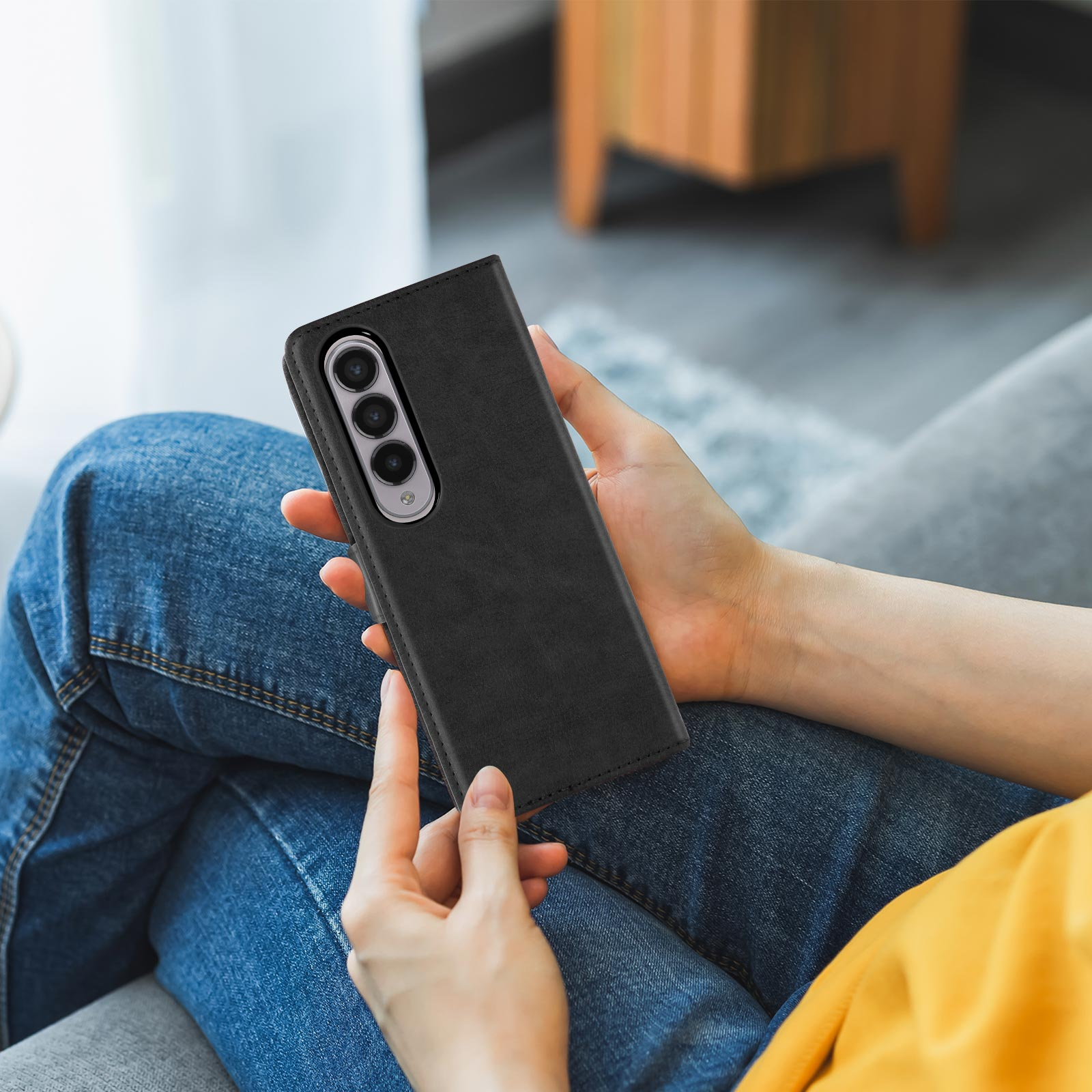 Coque de téléphone noire, ouverte et tenant un téléphone. Le téléphone est tenu par une personne.