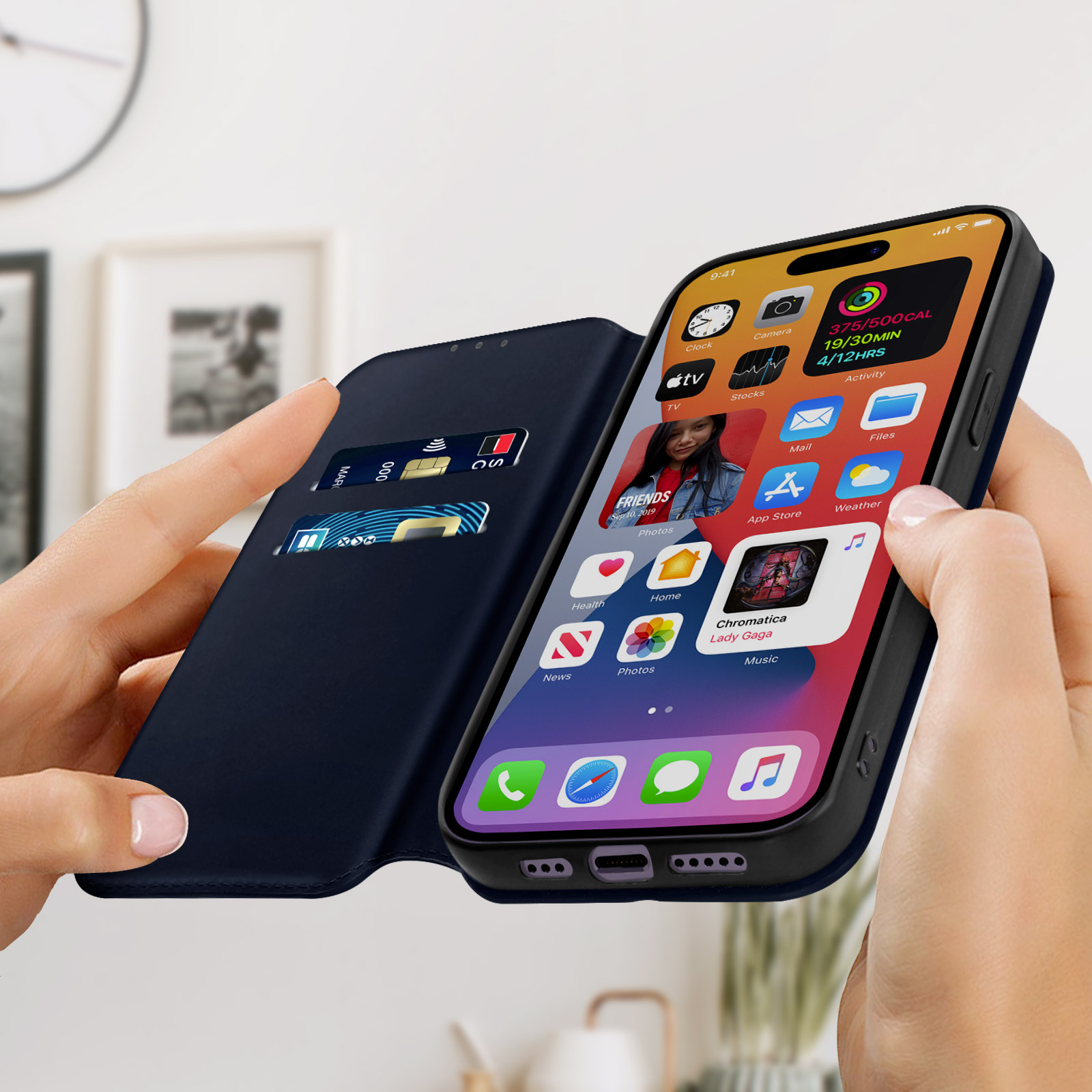 Een telefoon is open en toont apps. Een hand houdt de telefoon en de hoes vast. Kaarten zitten in een sleuf. De hoes is marineblauw.