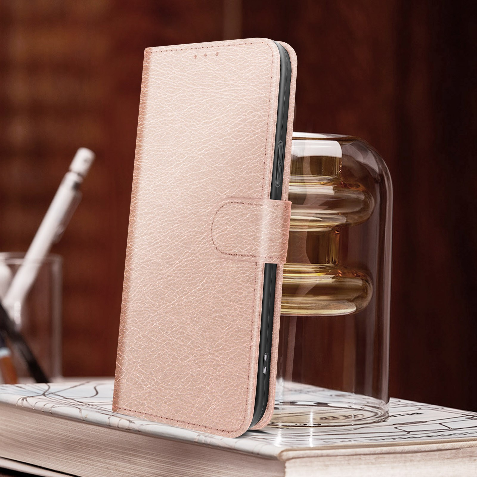 Custodia per telefono in pelle rosa, chiusa, con chiusura magnetica. Vicino a un vaso di vetro.