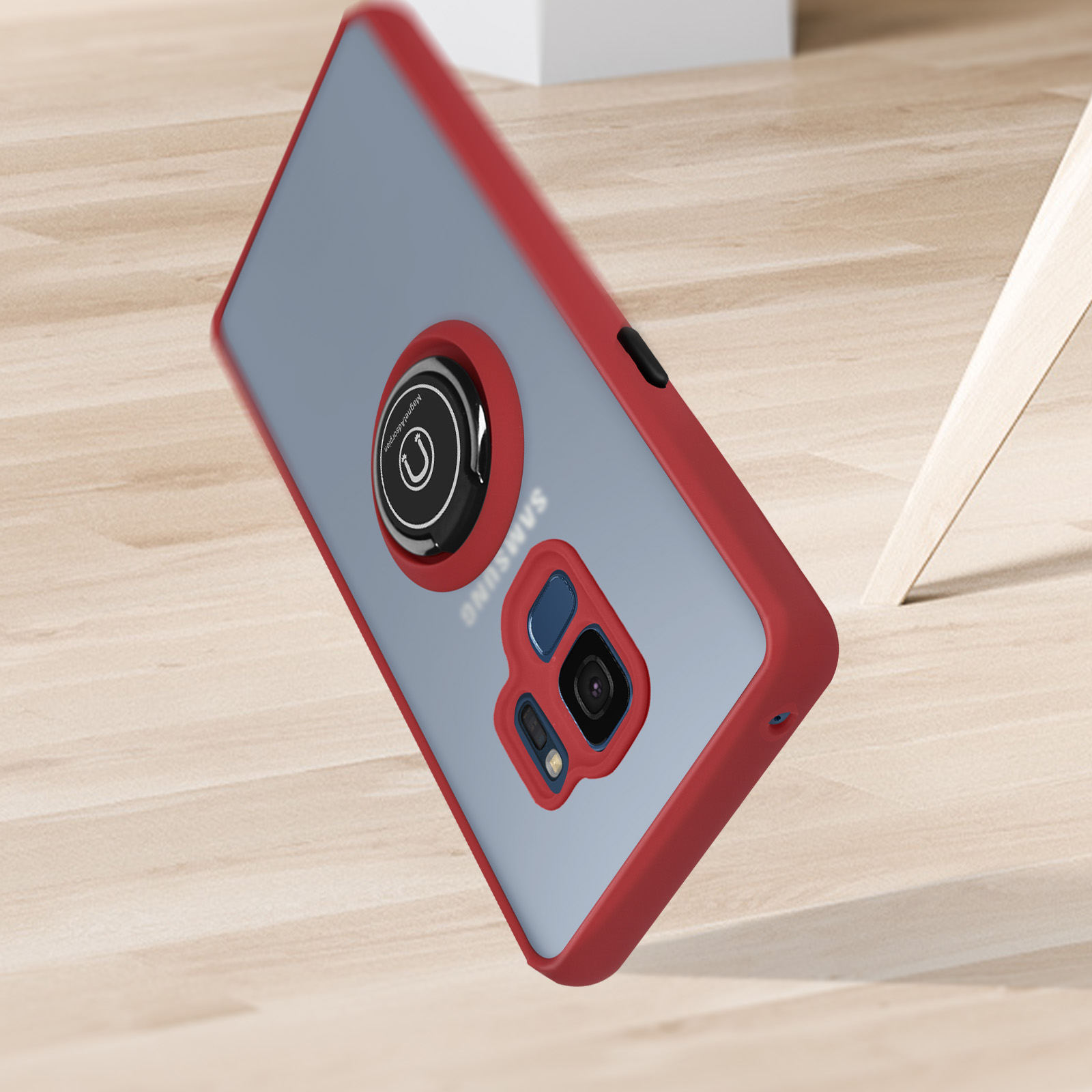 Eine rot umrandete Handyhülle mit angebrachtem Magnetring, die auf einer Holzoberfläche liegt.