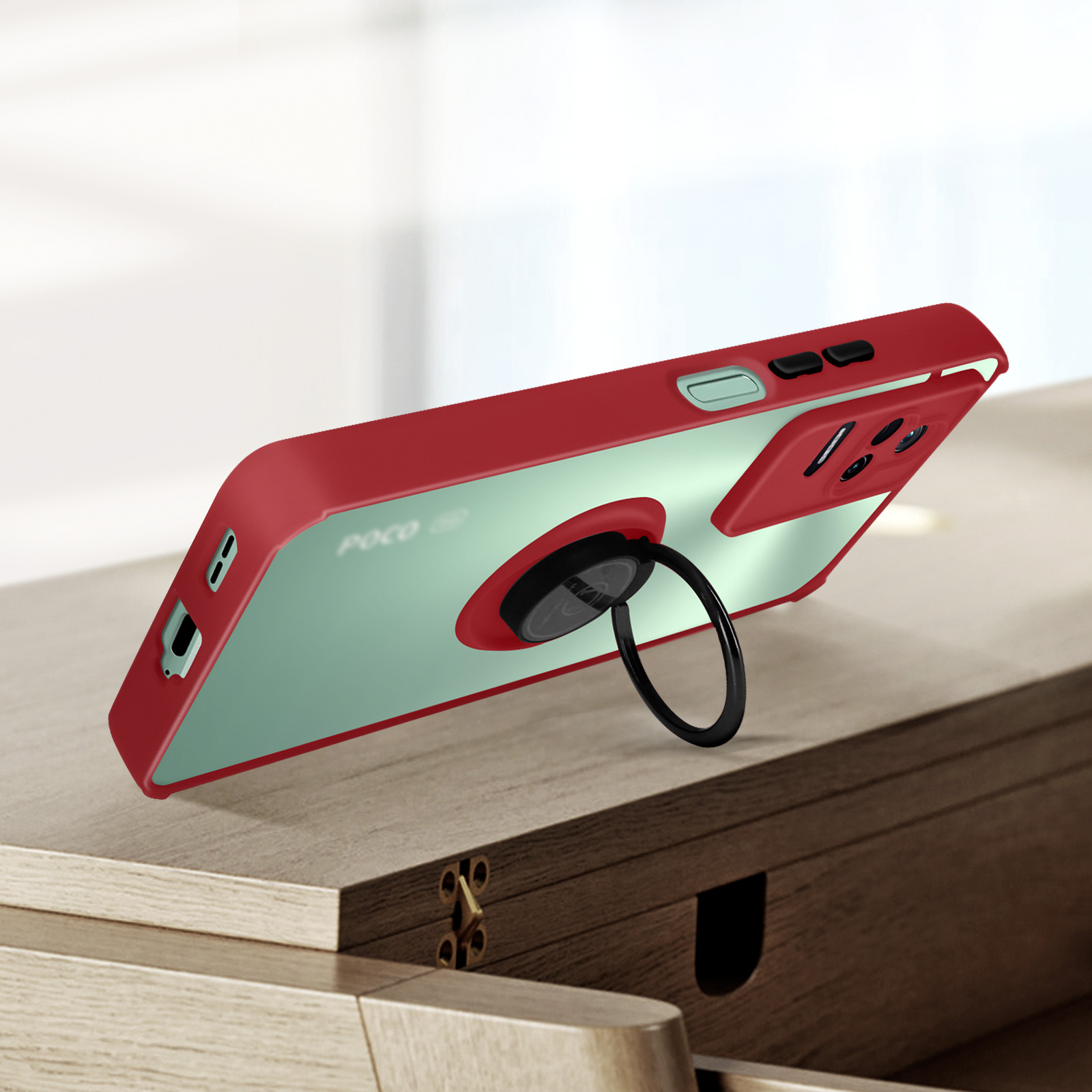 Custodia per telefono rossa e trasparente con anello di supporto nero su superficie in legno. Il telefono è inclinato.