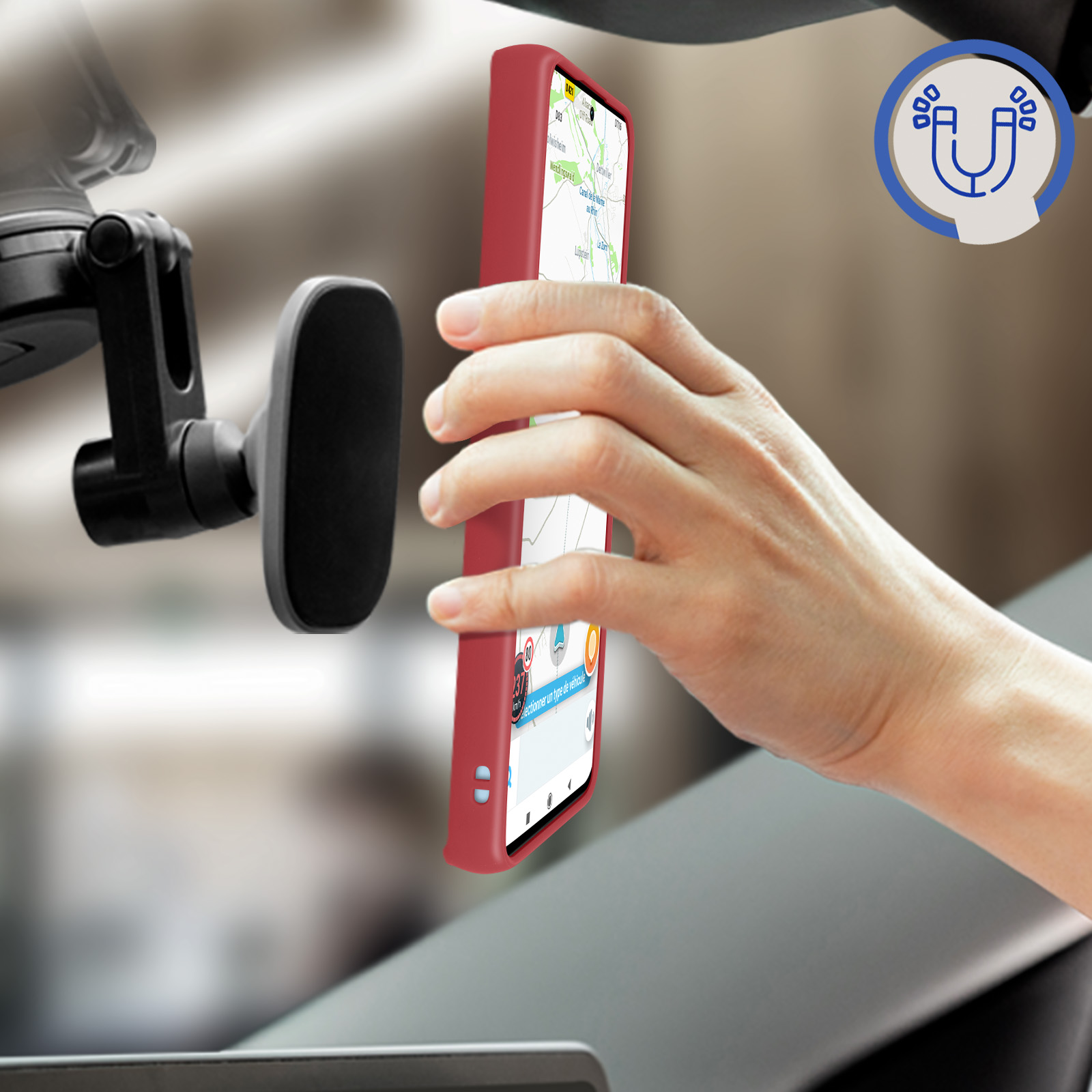 Eine Hand hält ein rotes Telefon in Richtung einer Windschutzscheibe. Ein magnetischer Telefonhalter und ein Magnet-Symbol sind sichtbar.