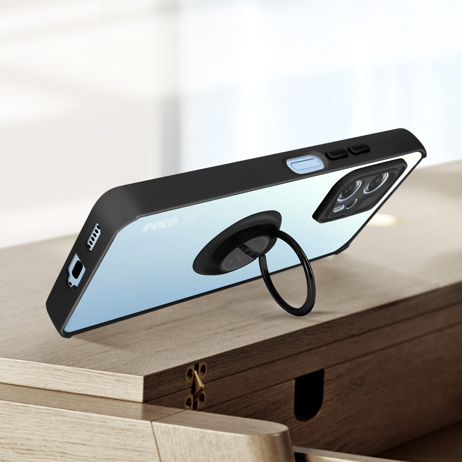 Ein Telefon in einer schwarzen Hülle mit Ringhalter, auf einem Holztisch, zeigt die Rückseite.