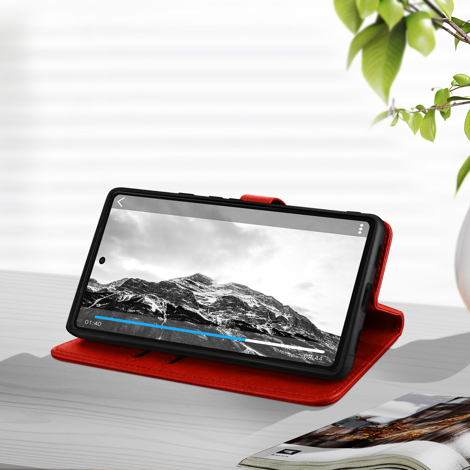 Tablette dans un étui en cuir rouge, ouverte, montrant une image en noir et blanc, sur une table en bois.