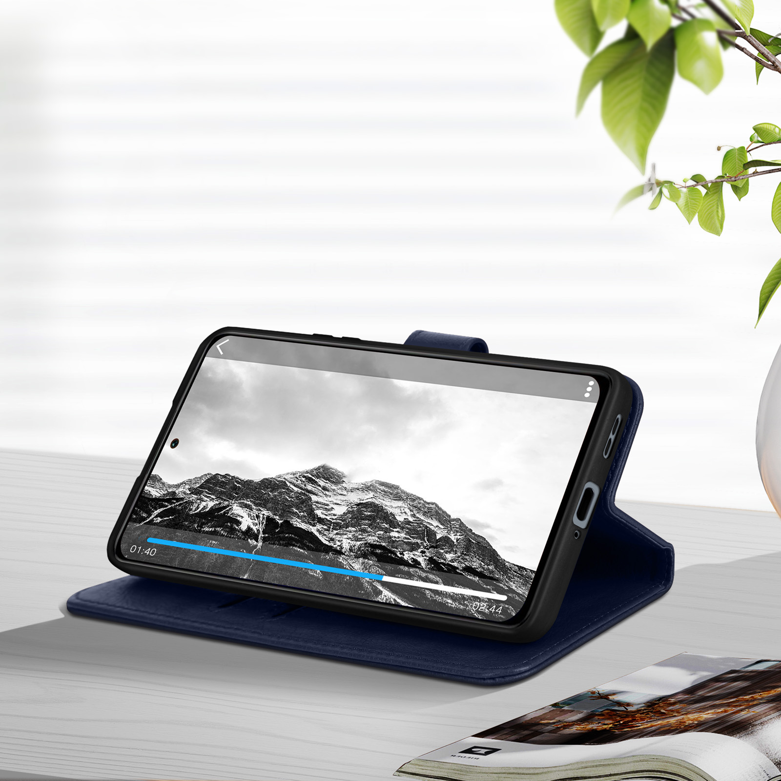 Un téléphone est posé sur une table, affichant une vidéo, avec un étui ouvert.