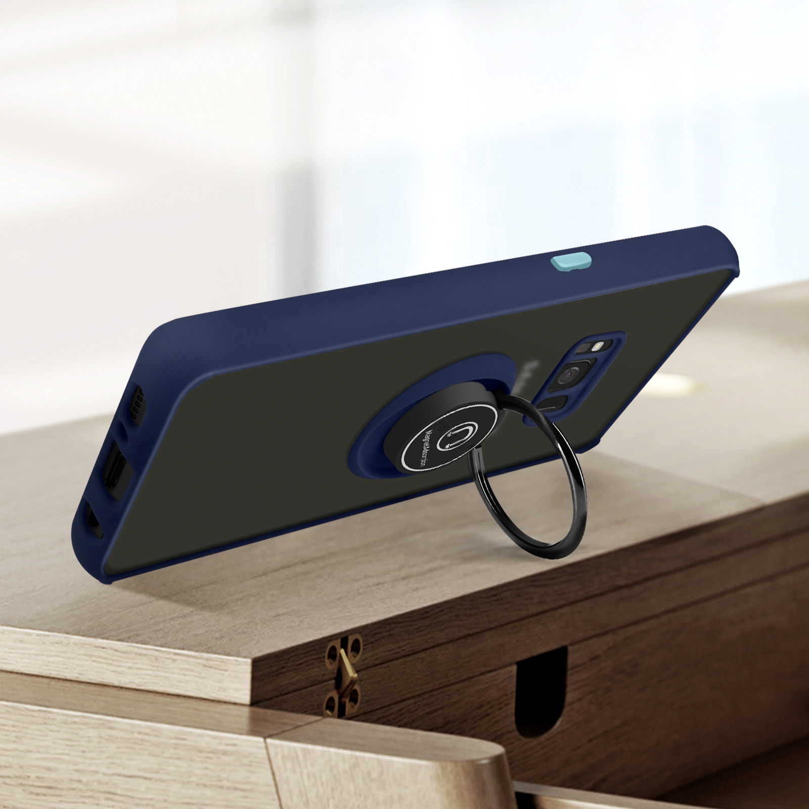 Een blauwe telefoonhoes met een zwarte ringhouder op een houten tafel.