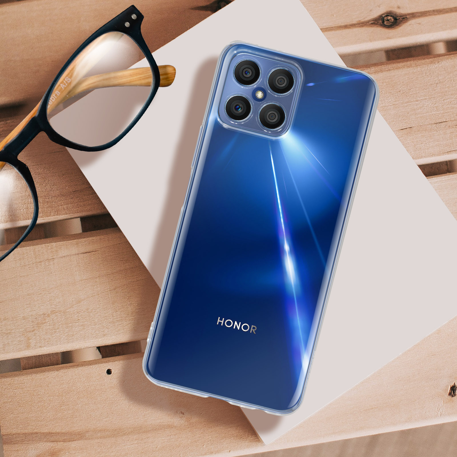 Smartphone blu in custodia trasparente su legno, con occhiali.