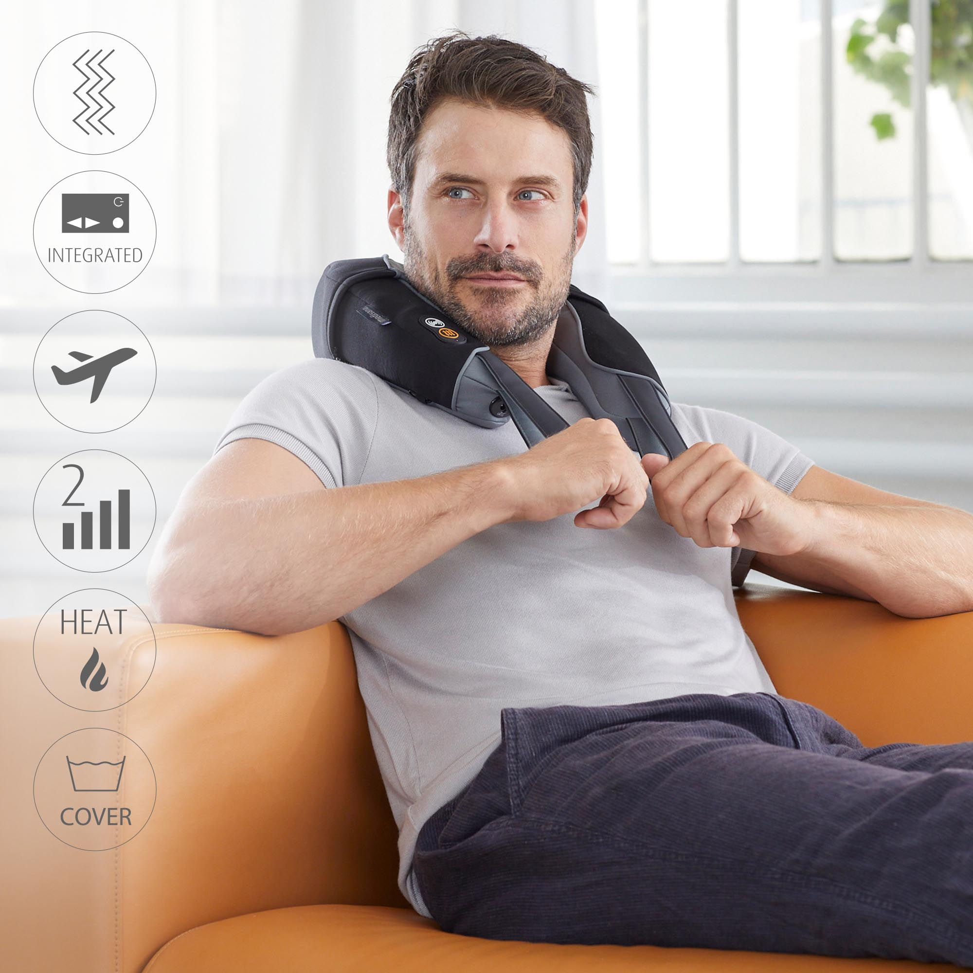 Mężczyzna siedzi na kanapie, nosząc czarny masażer szyi.