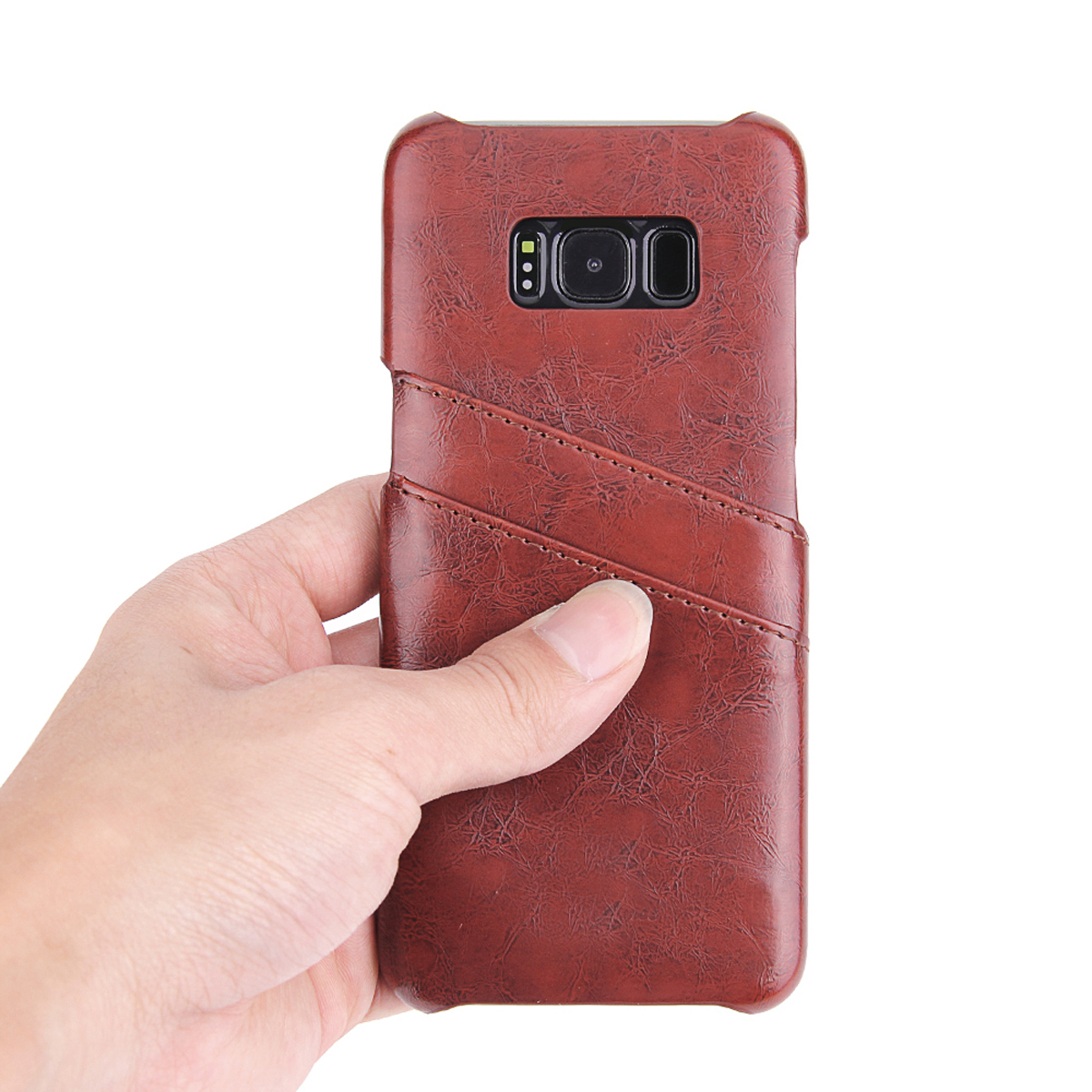 Eine Hand hält eine braune Leder-Handyhülle mit einem Telefon darin. Das Case hat ein Nahtdesign.