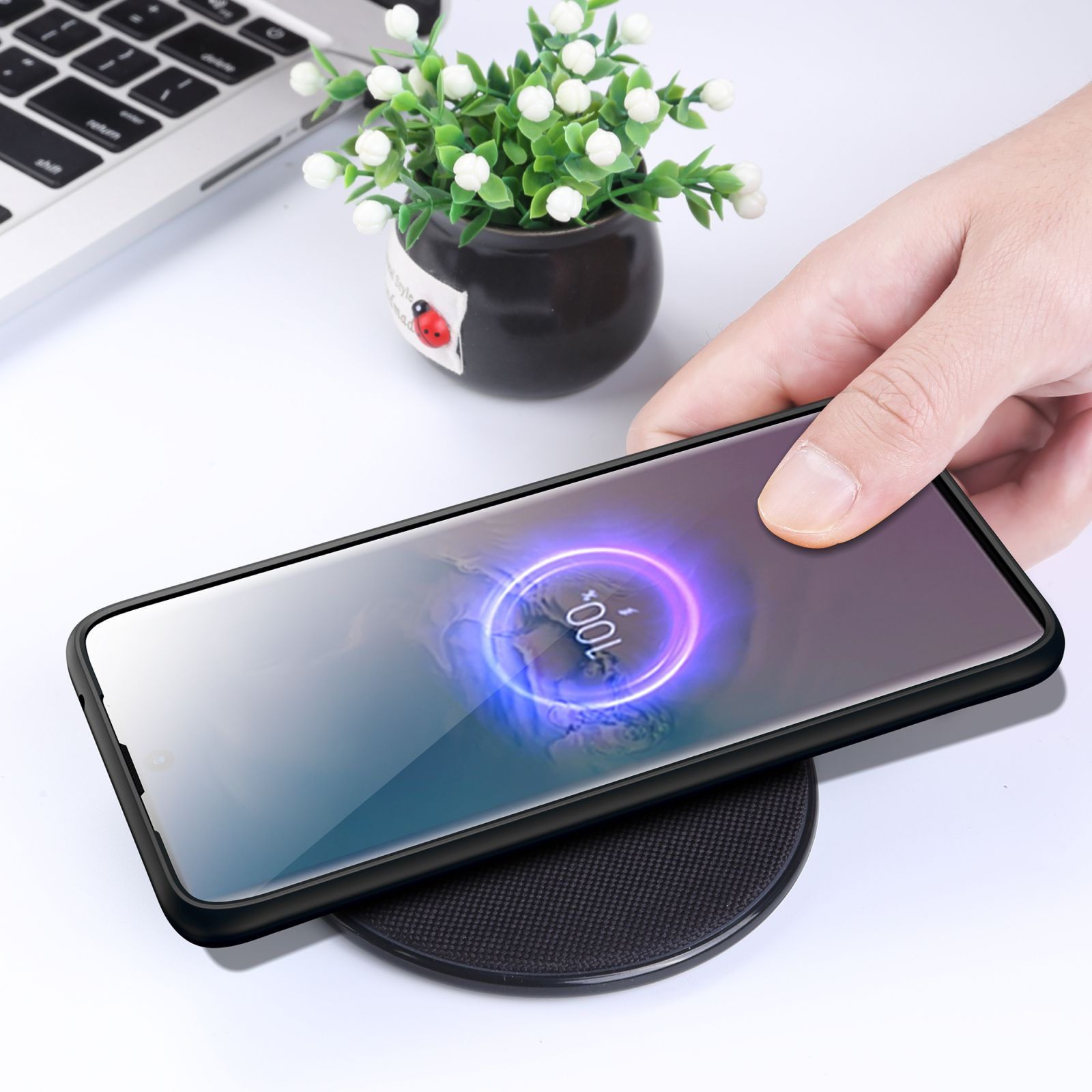 Ein Telefon auf einem kabellosen Ladegerät mit Ladeanzeige. Eine Hand ist dabei, es auf das Ladegerät zu legen.