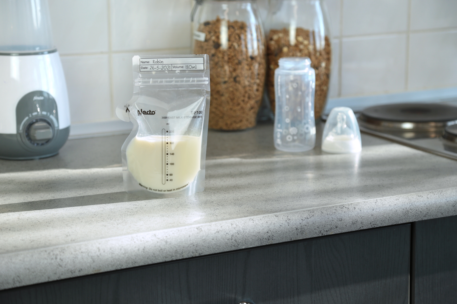 Breast milk bag with milk, and a baby bottle on a kitchen counter.