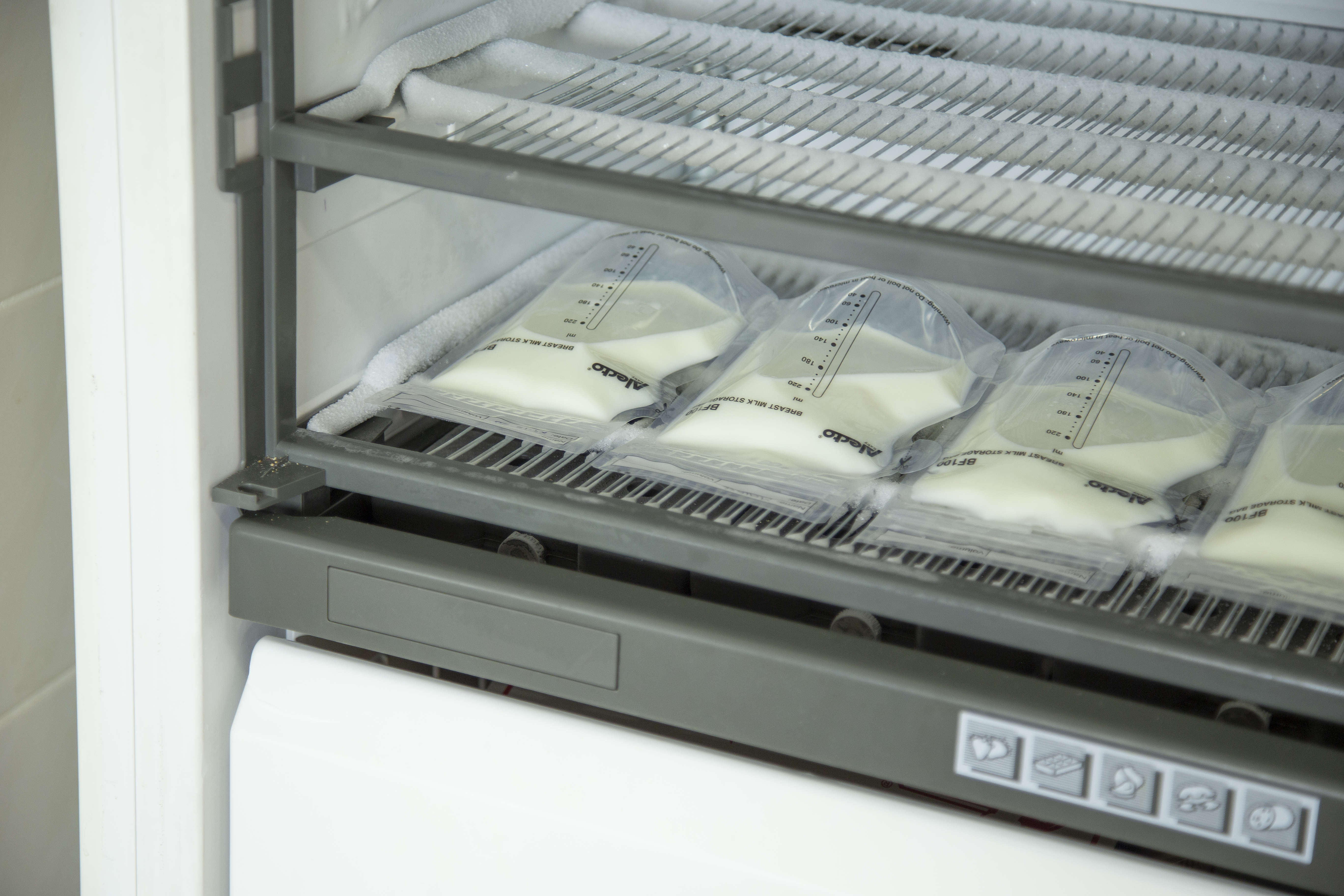 Bags of breast milk stored in a freezer, with a visible wire rack.