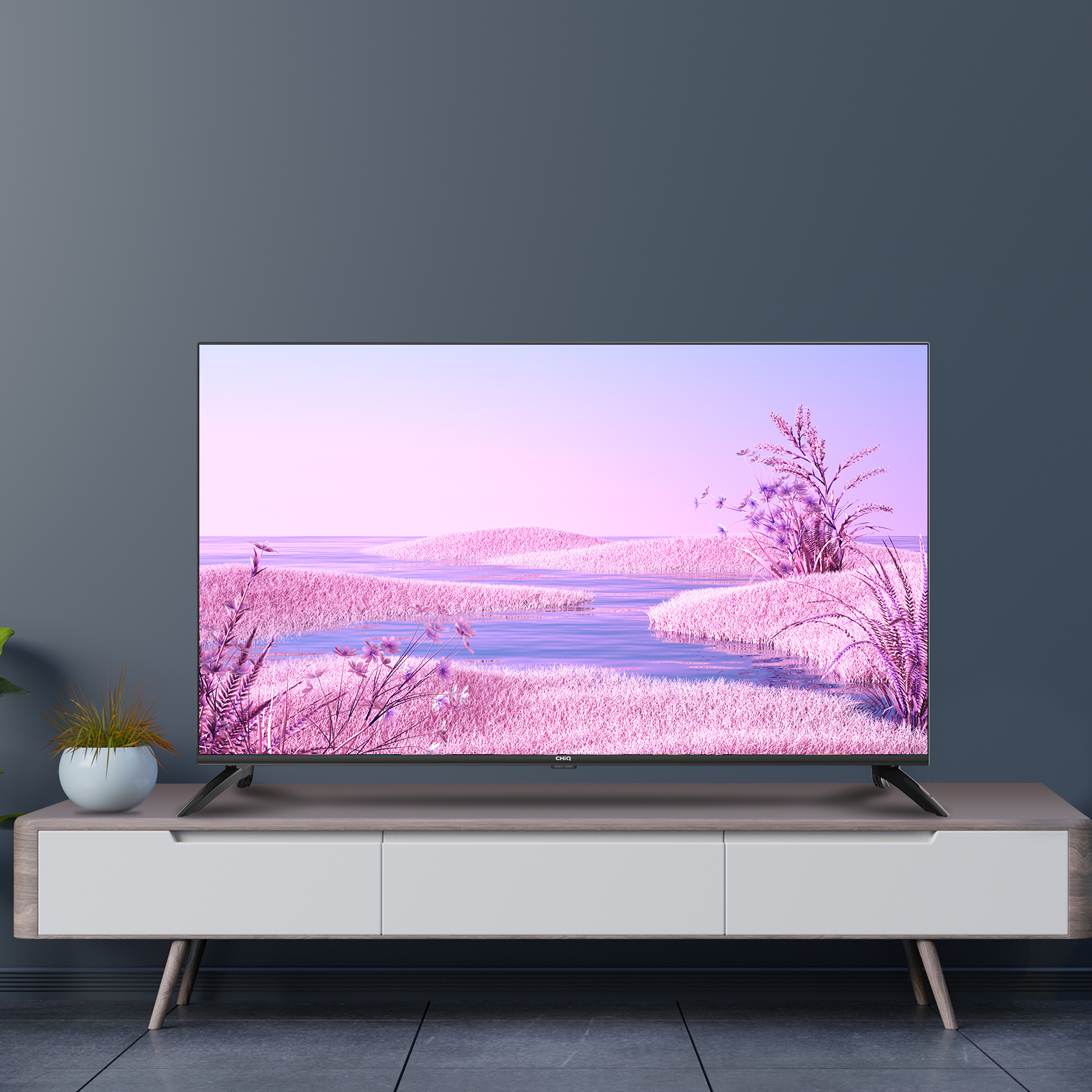 Fernseher auf einem weiß-grauen Schrank, der eine rosa Landschaft zeigt.