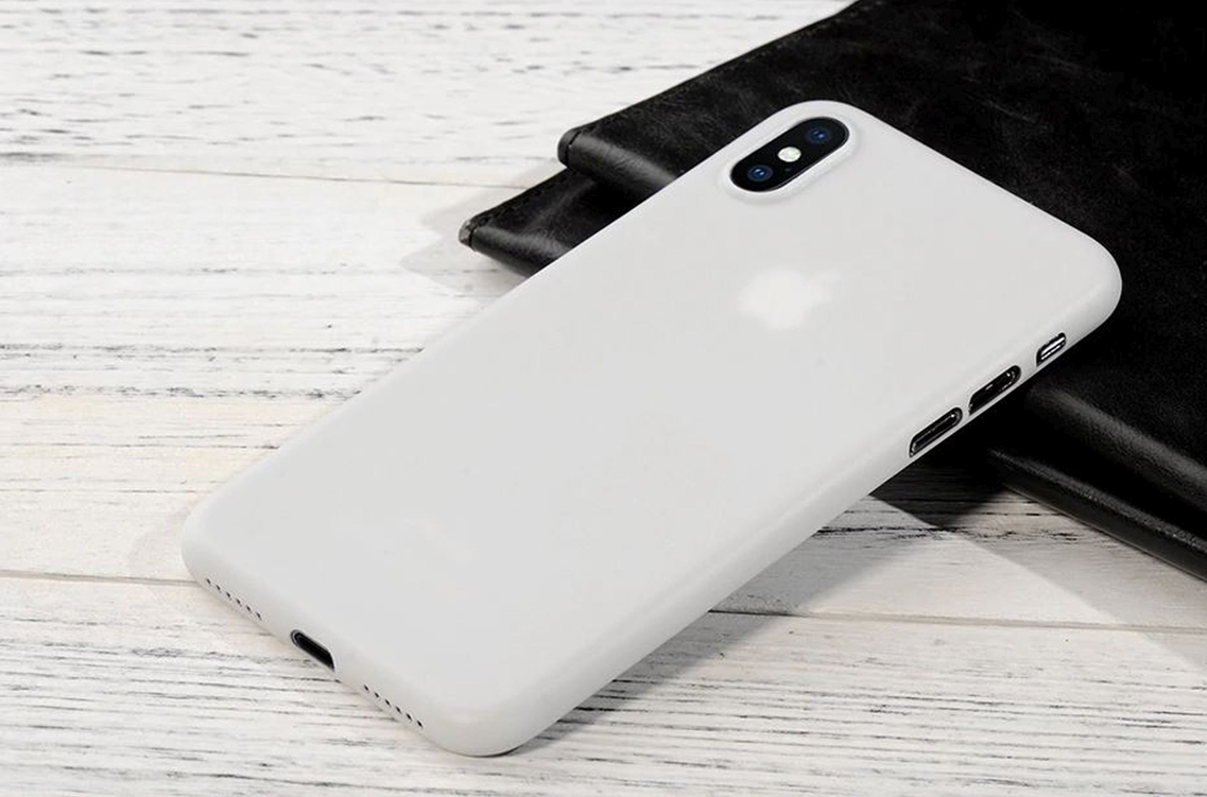 Weiße Handyhülle mit weißem Apple-Logo auf Holzoberfläche.