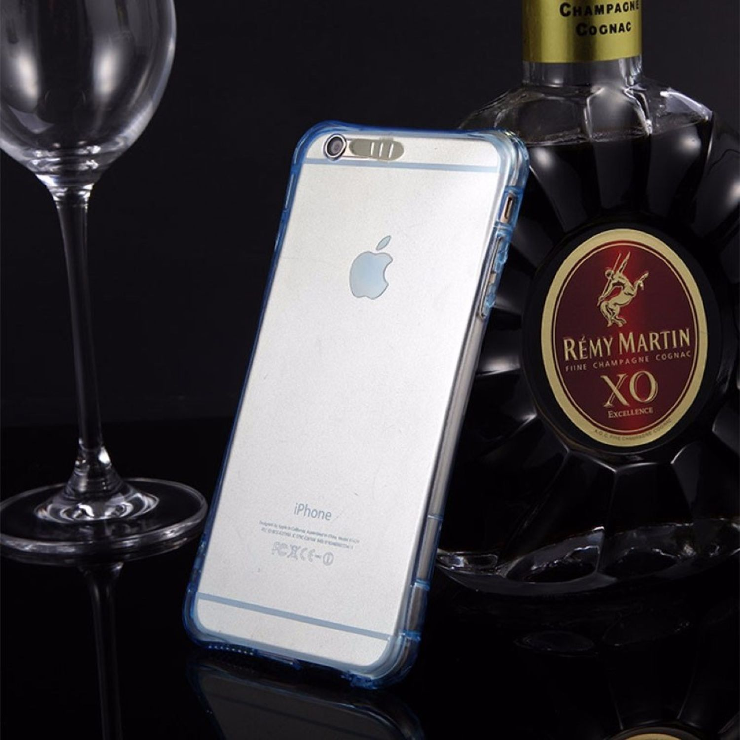 iPhone in einer transparenten Hülle, neben einem Glas und einer Cognac-Flasche.