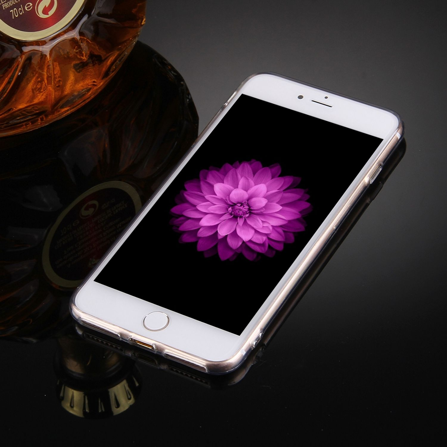 Weißes Telefon mit rosa Blume auf dem Bildschirm, auf dunkler, reflektierender Oberfläche.