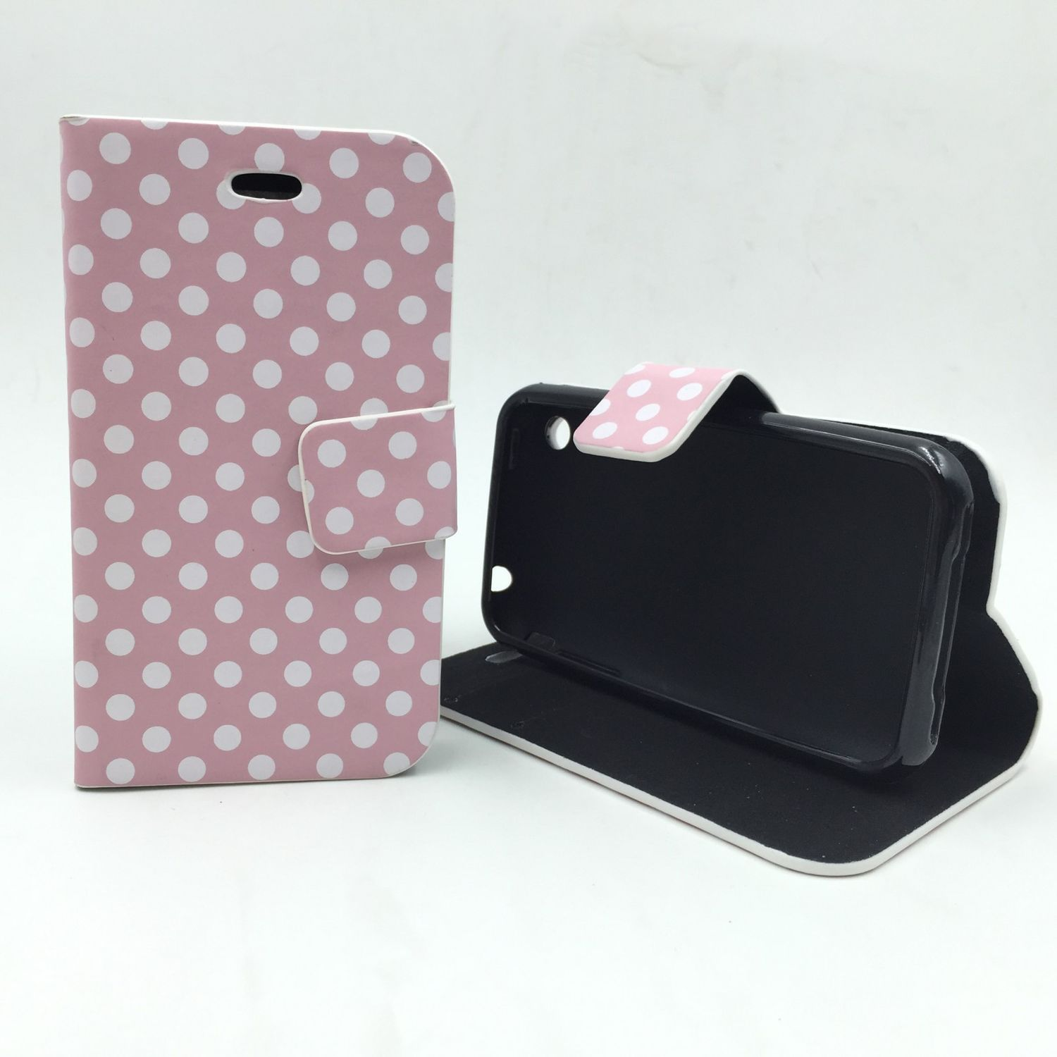 Pinkfarbene Handyhülle mit Polka Dots, geöffnet, um ein schwarzes Telefon zu zeigen. Weißer Hintergrund.