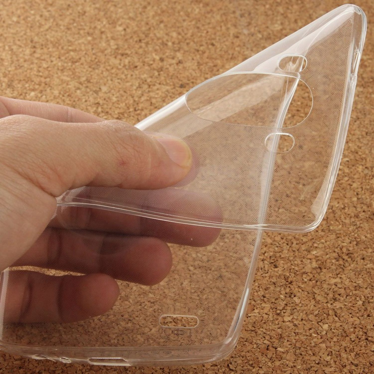 Eine Hand hält eine durchsichtige Handyhülle. Der Koffer ist transparent und scheint flexibel zu sein. Brauner Hintergrund.