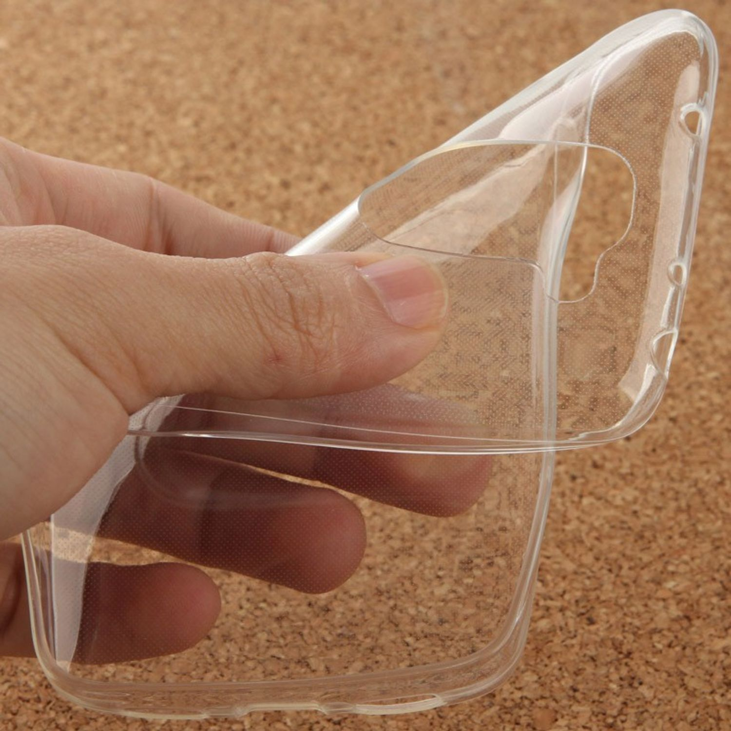 Hand, die eine transparente Handyhülle hält, auf strukturiertem Hintergrund. Hülle ist offen.