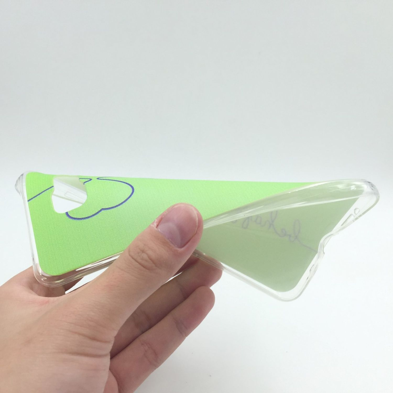 Hand hält eine Handyhülle mit grünem Design. Die Hülle ist transparent.