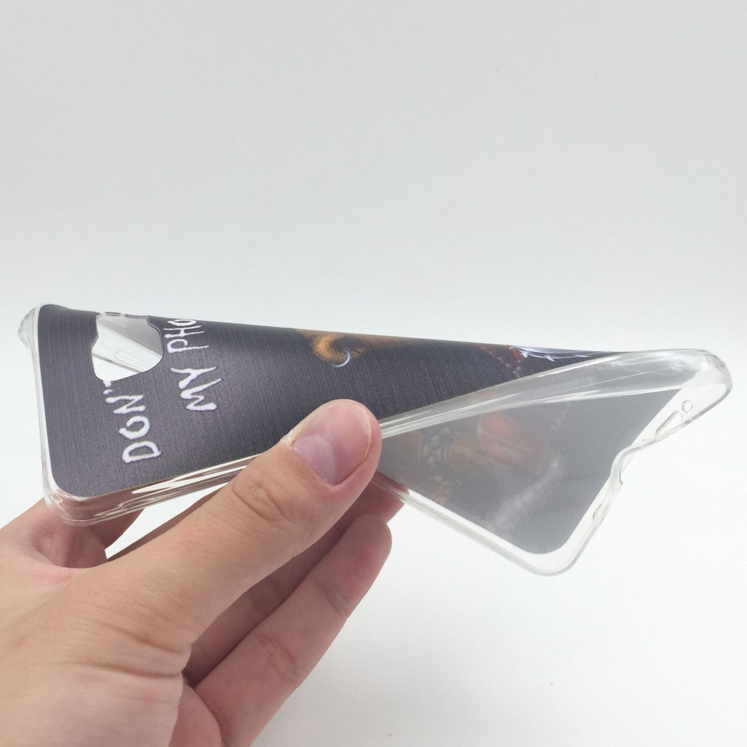 Eine Hand, die eine transparente Handyhülle mit dunklem Aufdruck hält, weißer Hintergrund.