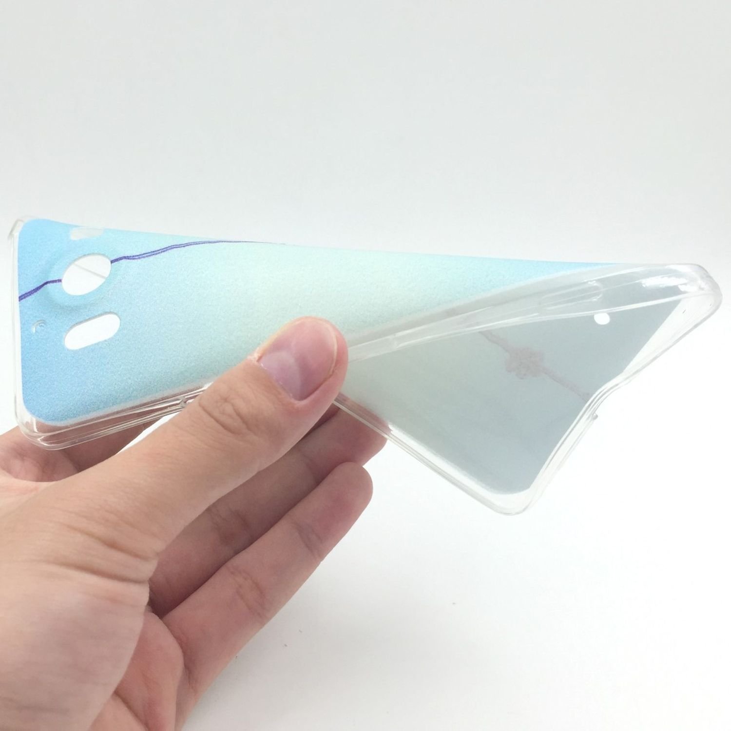 Hand hält eine transparente Handyhülle mit blau-weißem Design, weißer Hintergrund.