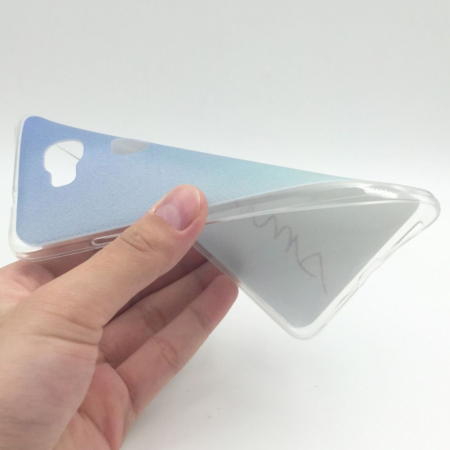 Hand hält eine transparente Handyhülle mit blauem Farbverlauf. Weißer Hintergrund.