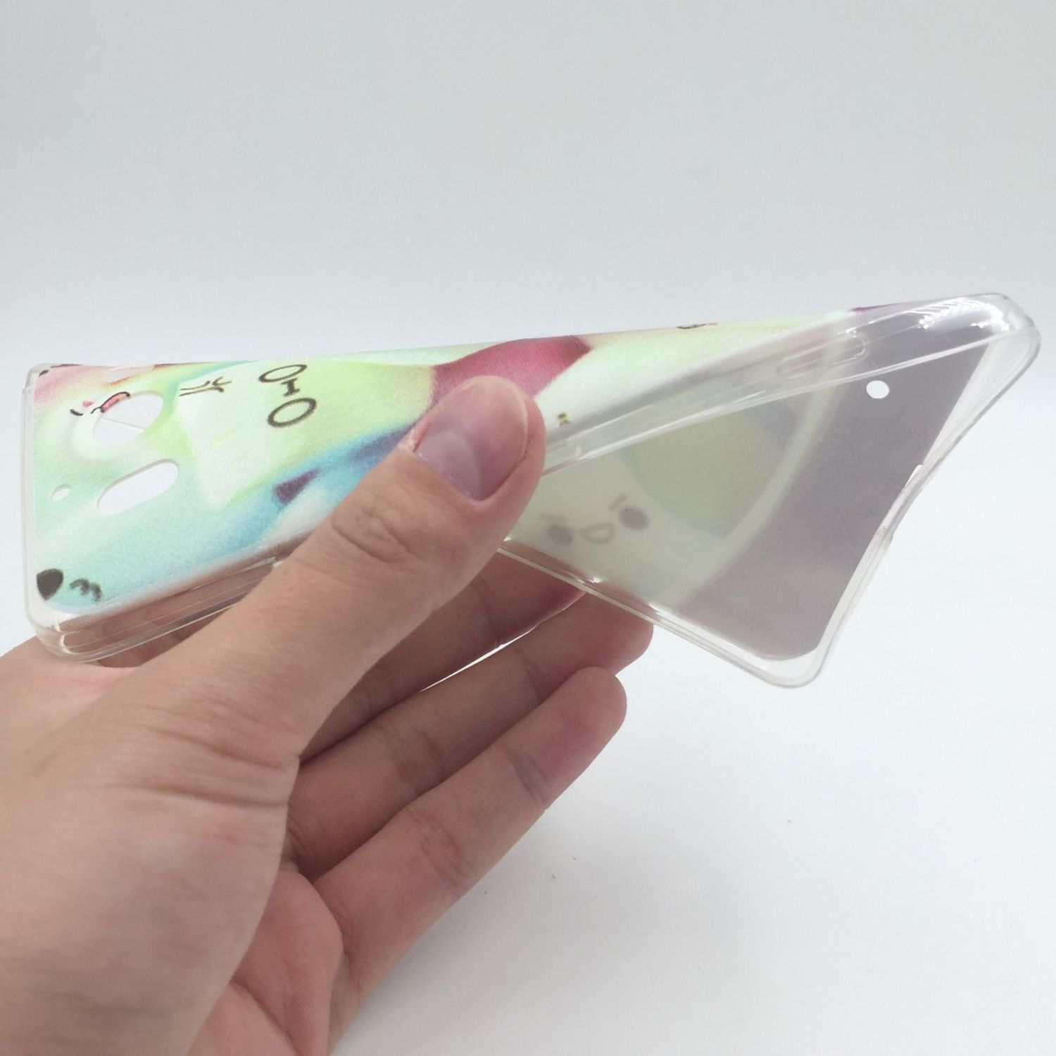 Eine Hand hält eine transparente Handyhülle mit Cartoon-Design vor weißem Hintergrund.