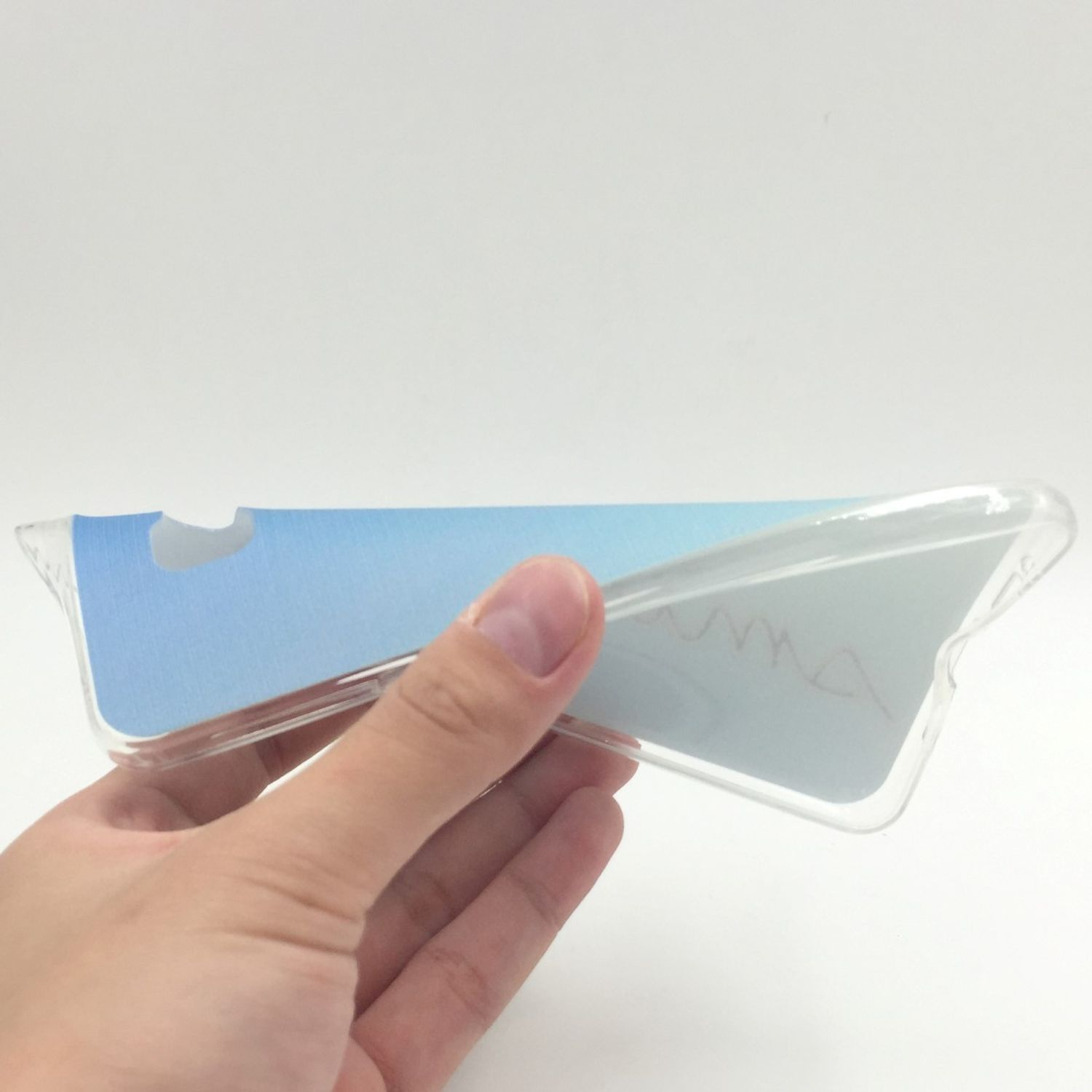 Eine Hand hält eine transparente Handyhülle. Die Hülle hat ein blau-weißes Design. Der Hintergrund ist weiß.