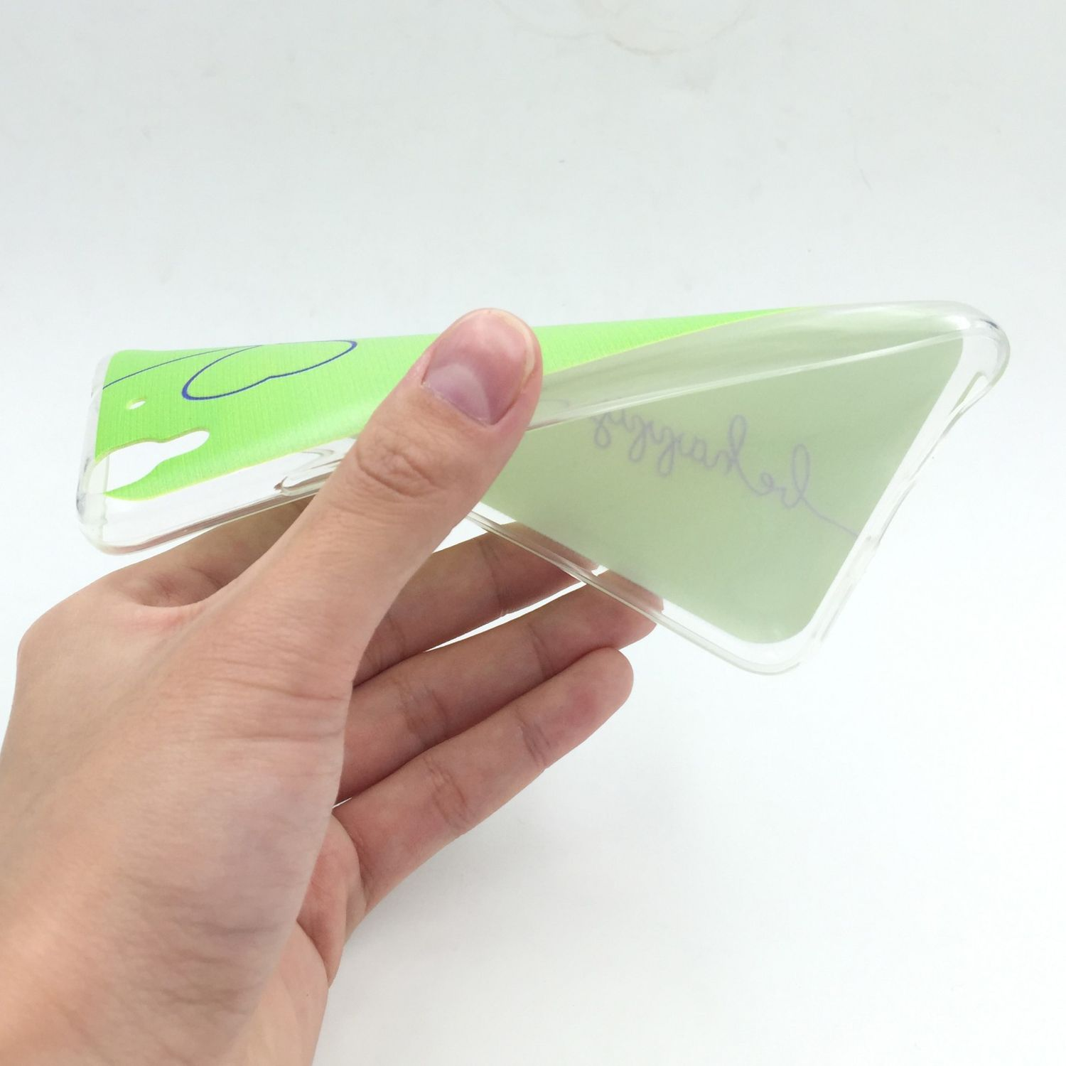 Hand hält eine transparente Handyhülle mit grünem Design, weißer Hintergrund.