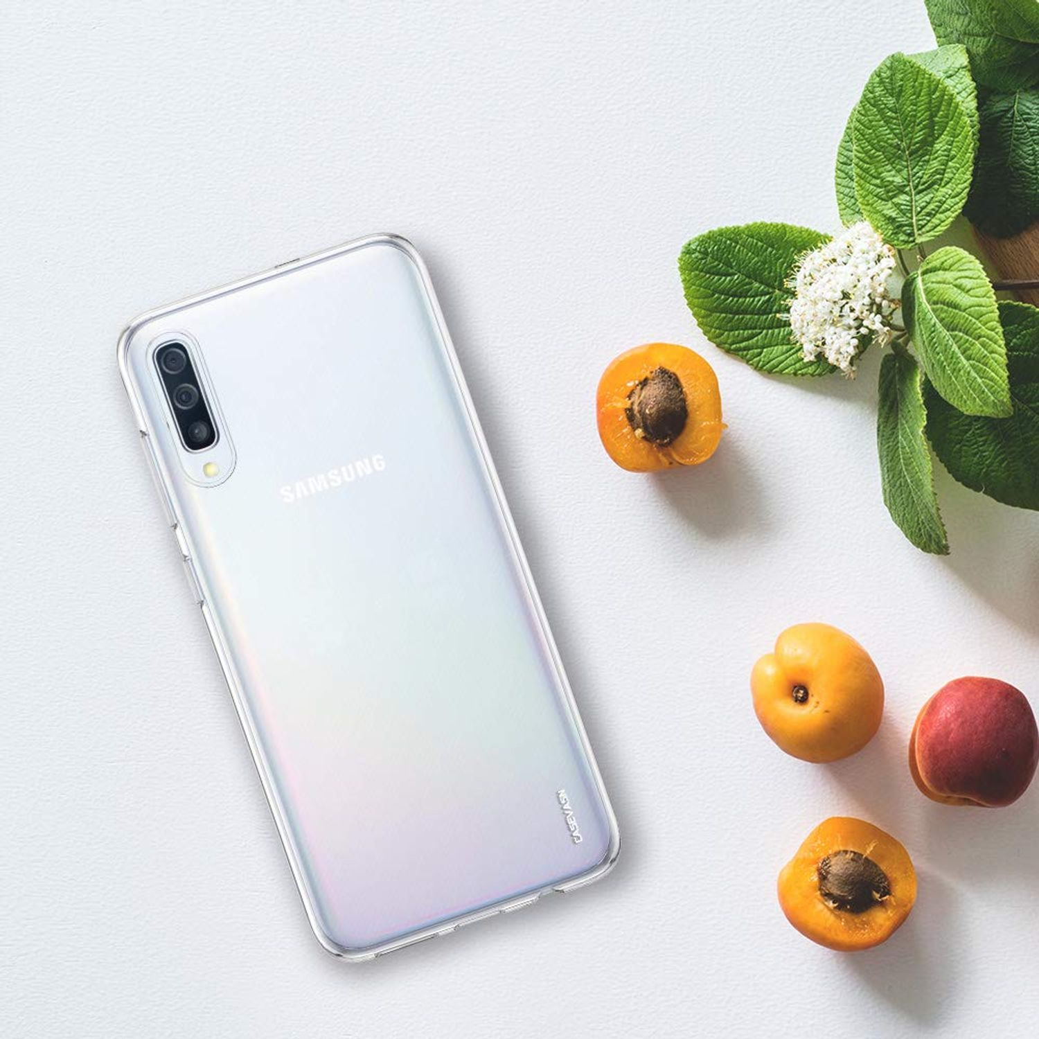 Weißes Telefon und Obst. Ein Samsung-Telefon mit Aprikosen und Blumen auf weißer Oberfläche.