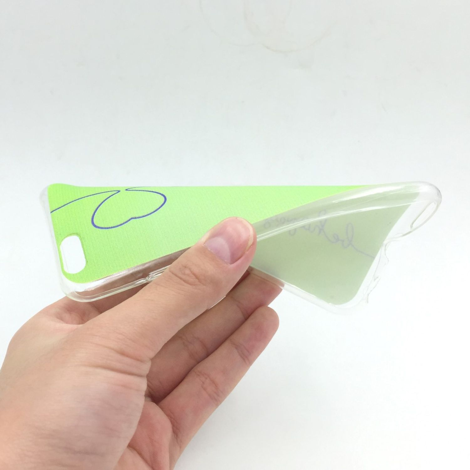Hand hält eine transparente Handyhülle mit grünem und blauem Design.