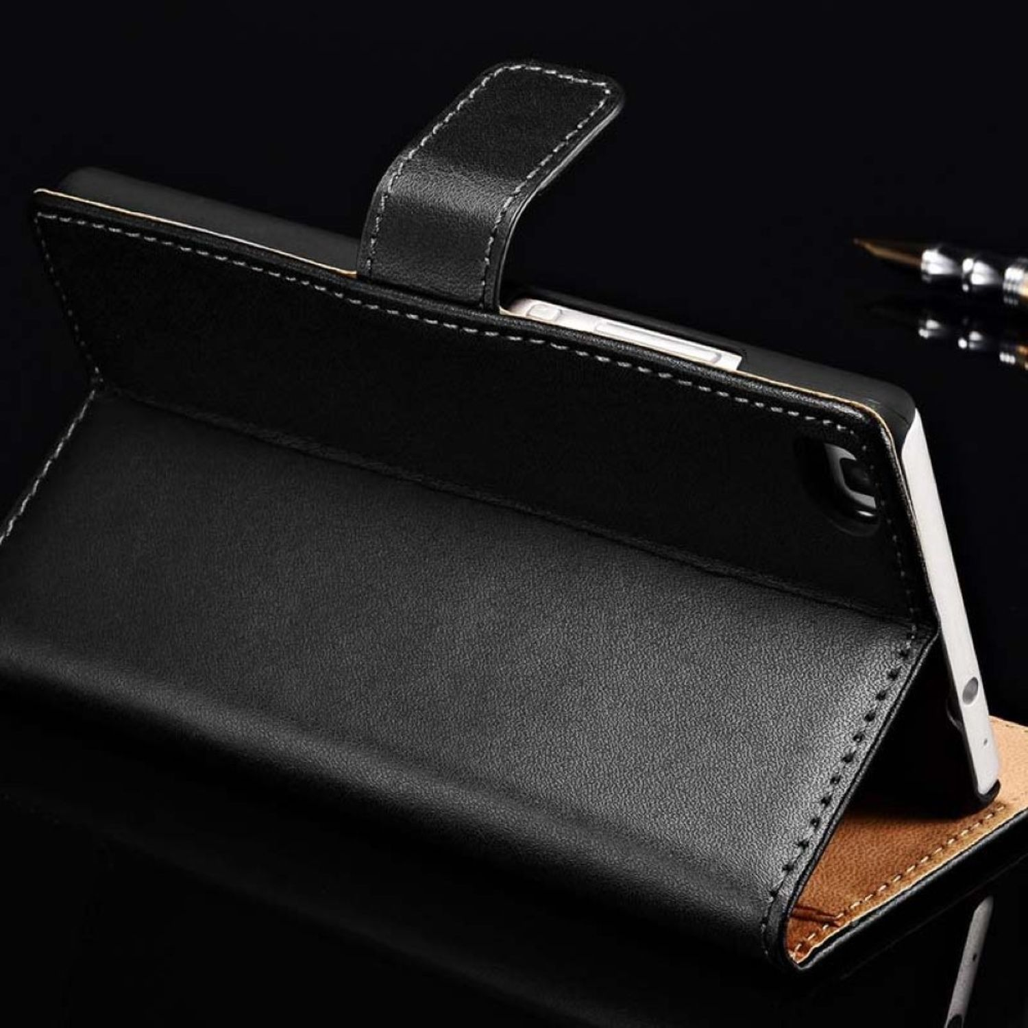 Schwarze Leder-Handyhülle mit Telefon darin. Die Hülle ist offen. Schwarzer Hintergrund.